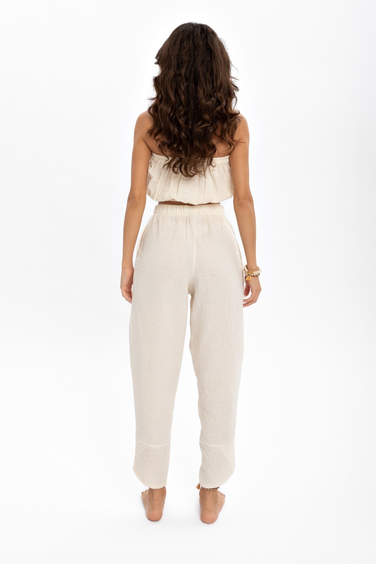 A pair of hand woven organic cotton pants in soft, natural colors, showcasing a high waist and elastic waistband, perfect for comfort and style.