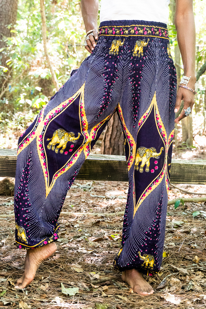 A pair of vibrant purple boho harem pants featuring intricate peacock and elephant patterns, made from lightweight rayon with an elastic waist and ankle.