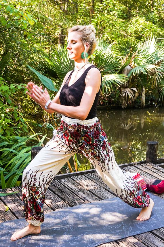 A pair of White Floral Women Boho Pants featuring a vibrant floral pattern, elastic waist, and ankle cuffs, perfect for yoga and casual wear.