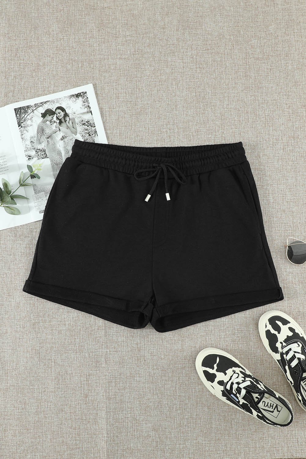 A pair of stylish black cuffed lounge shorts for women featuring a tie waist and side pockets, perfect for summer wear.