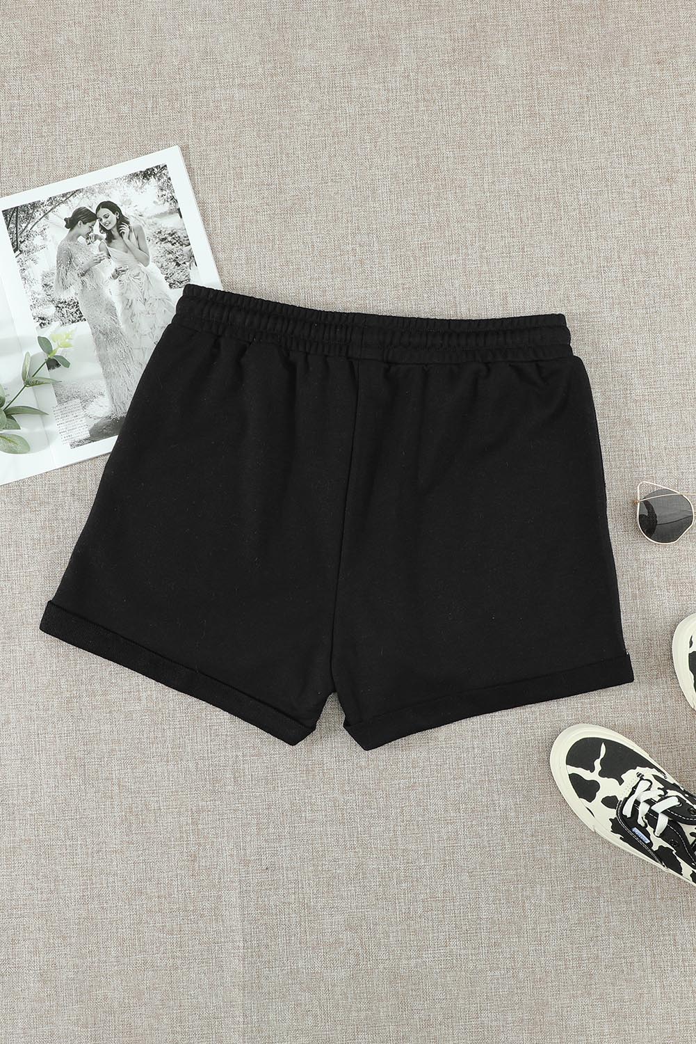 A pair of stylish black cuffed lounge shorts for women featuring a tie waist and side pockets, perfect for summer wear.