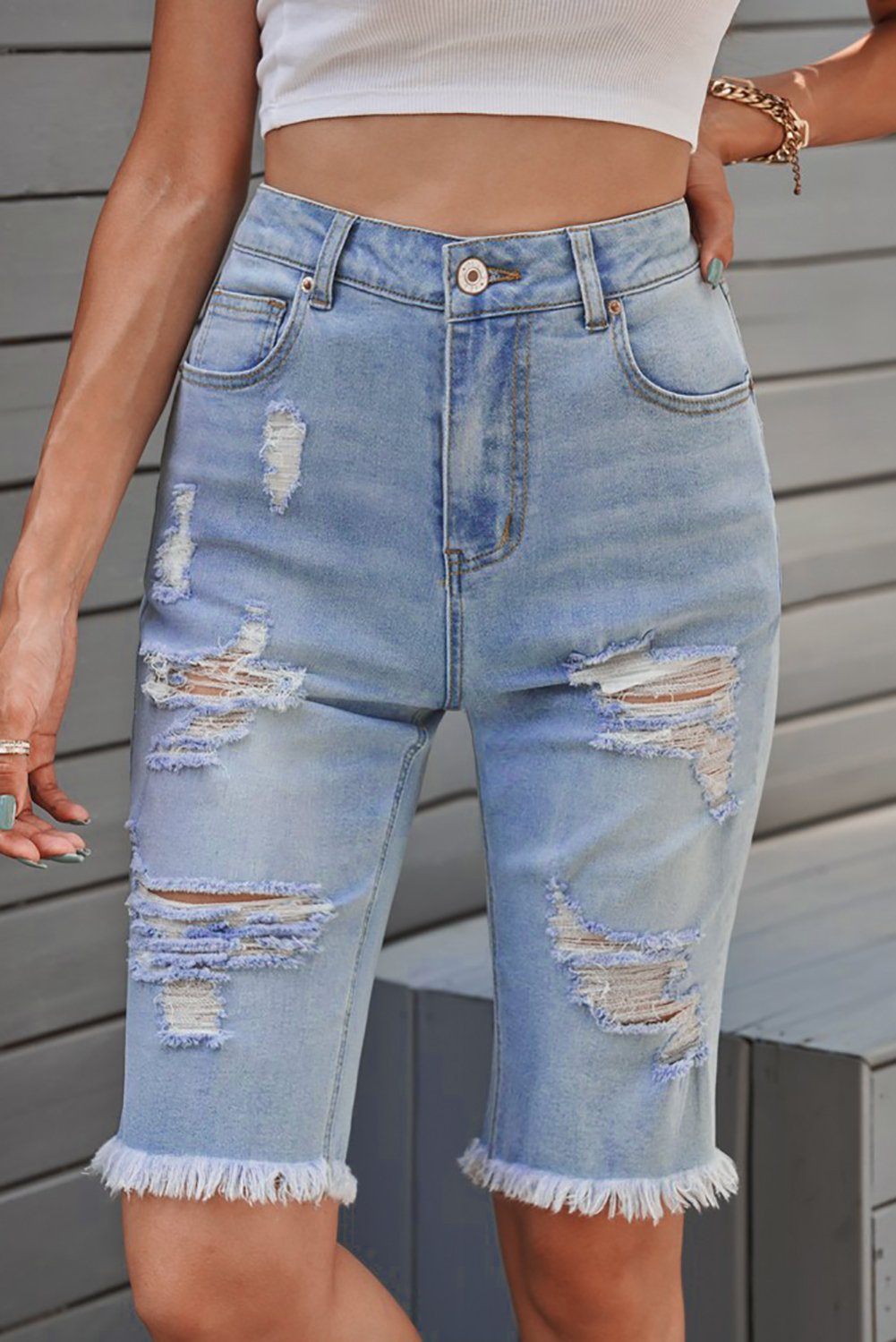 A pair of women's light blue distressed jeans Bermuda shorts featuring a raw hem, pockets, and a casual style, perfect for summer wear.