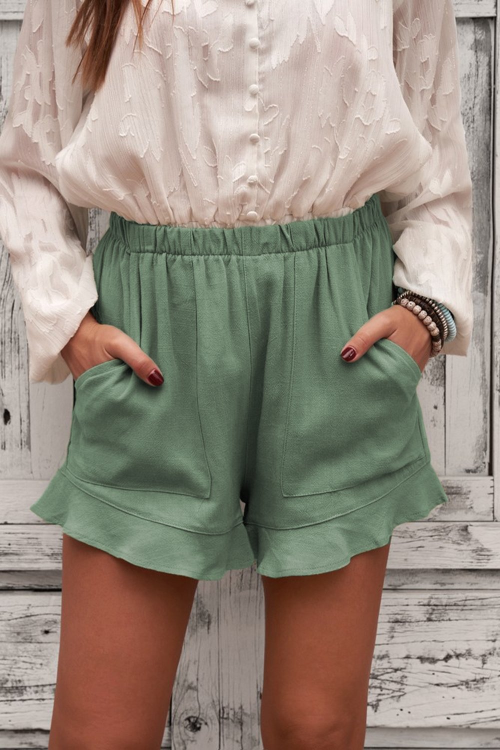 A pair of Women's Summer Pocketed Flutter Green Linen Cotton Shorts featuring ruffled details and side pockets, perfect for summer wear.