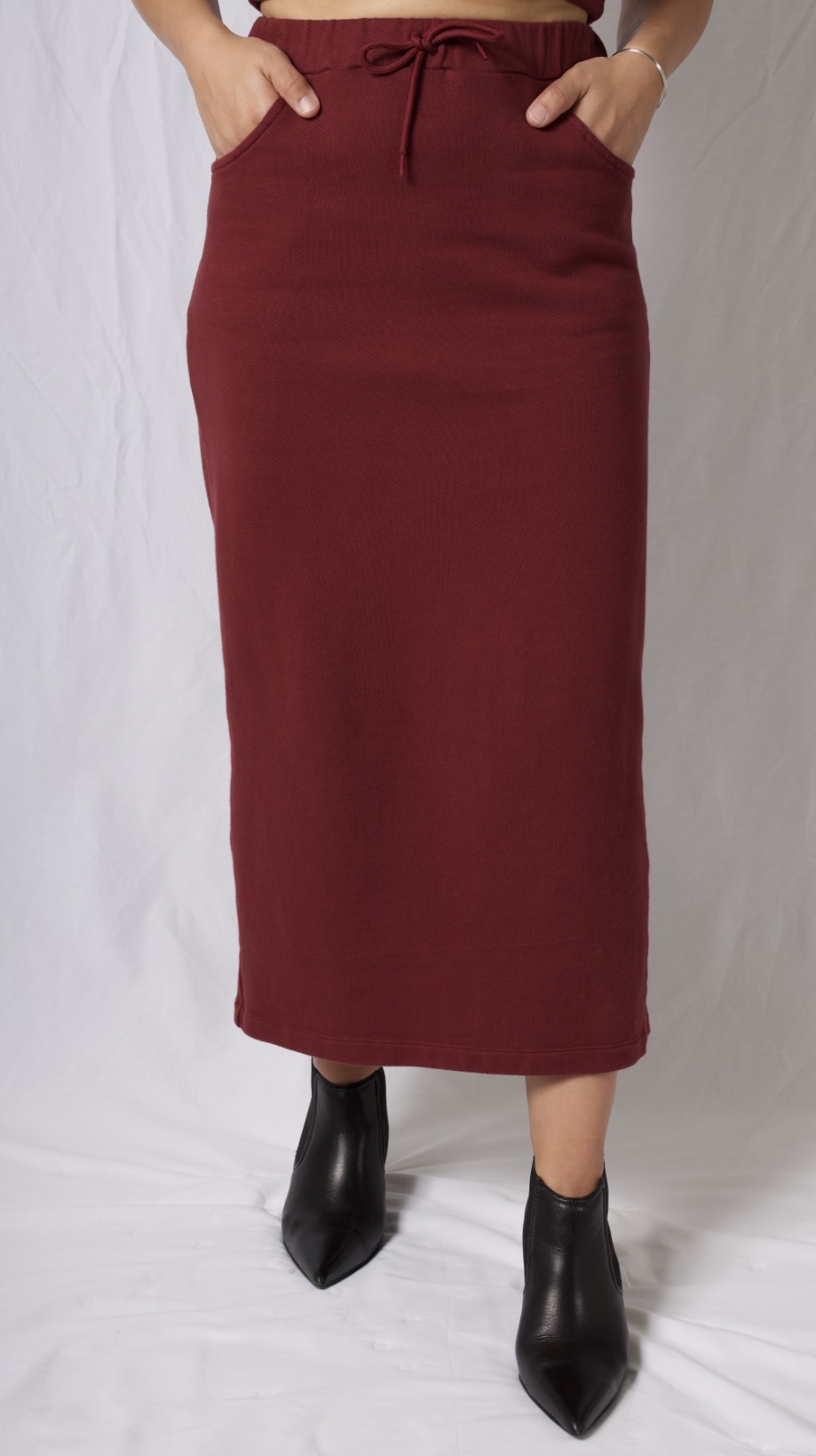 A stylish cotton midi skirt featuring an elastic waistband, deep pockets, and a braided brick red drawstring, perfect for versatile outfits.