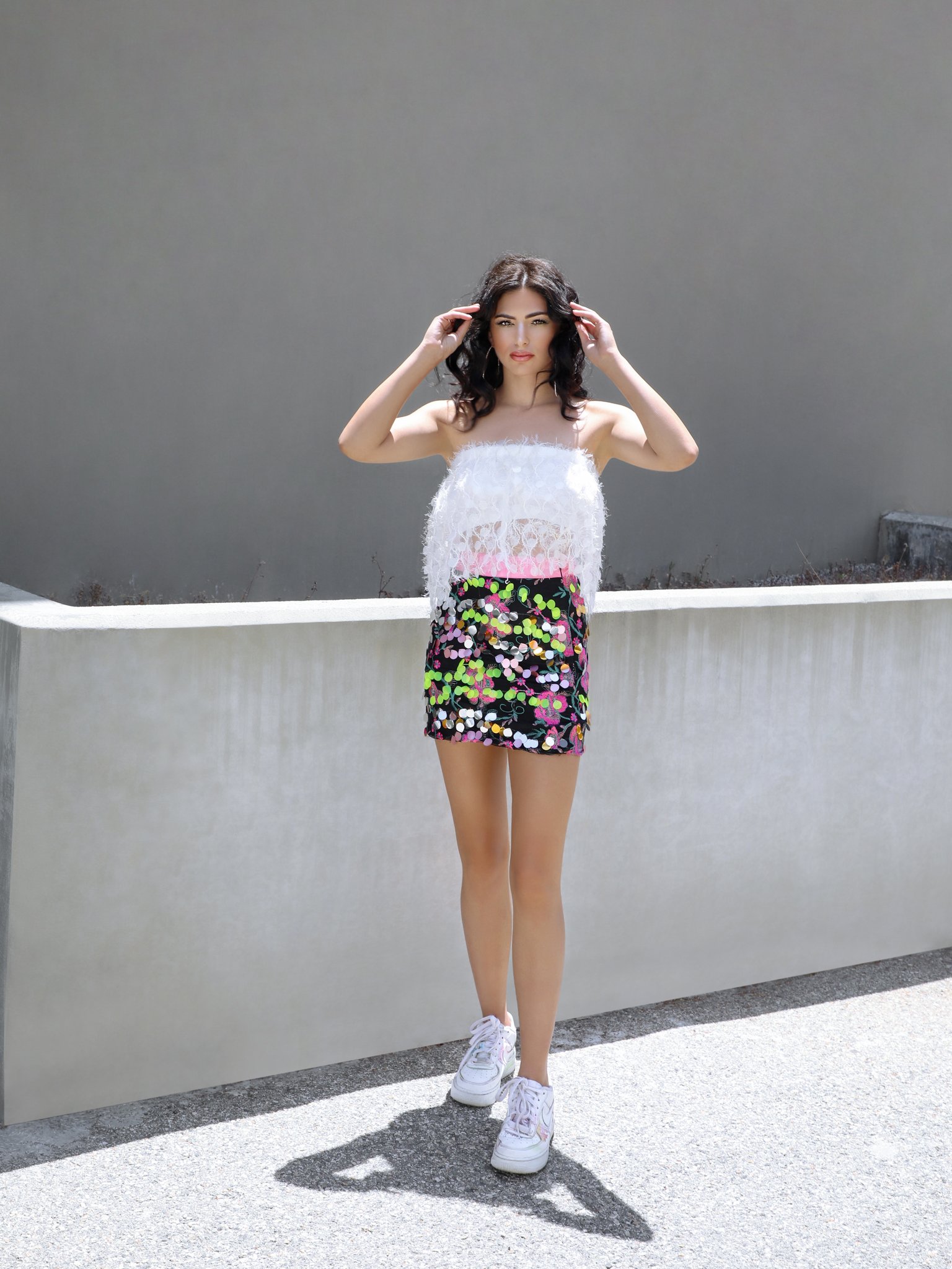 A glamorous black mini skirt adorned with colorful embroidery and sparkling Payette sequins, featuring a high waist and pink trim.