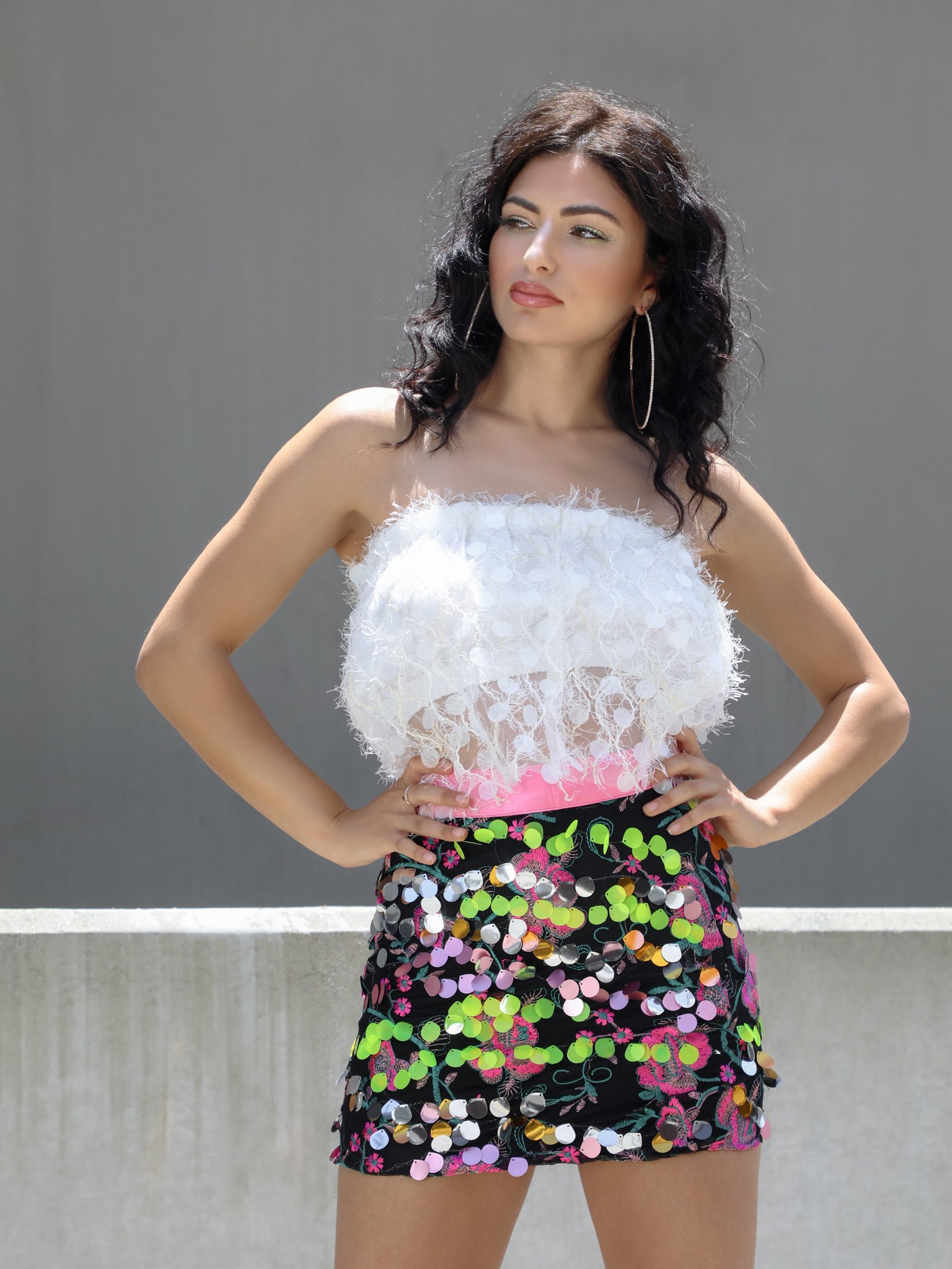 A glamorous black mini skirt adorned with colorful embroidery and sparkling Payette sequins, featuring a high waist and pink trim.