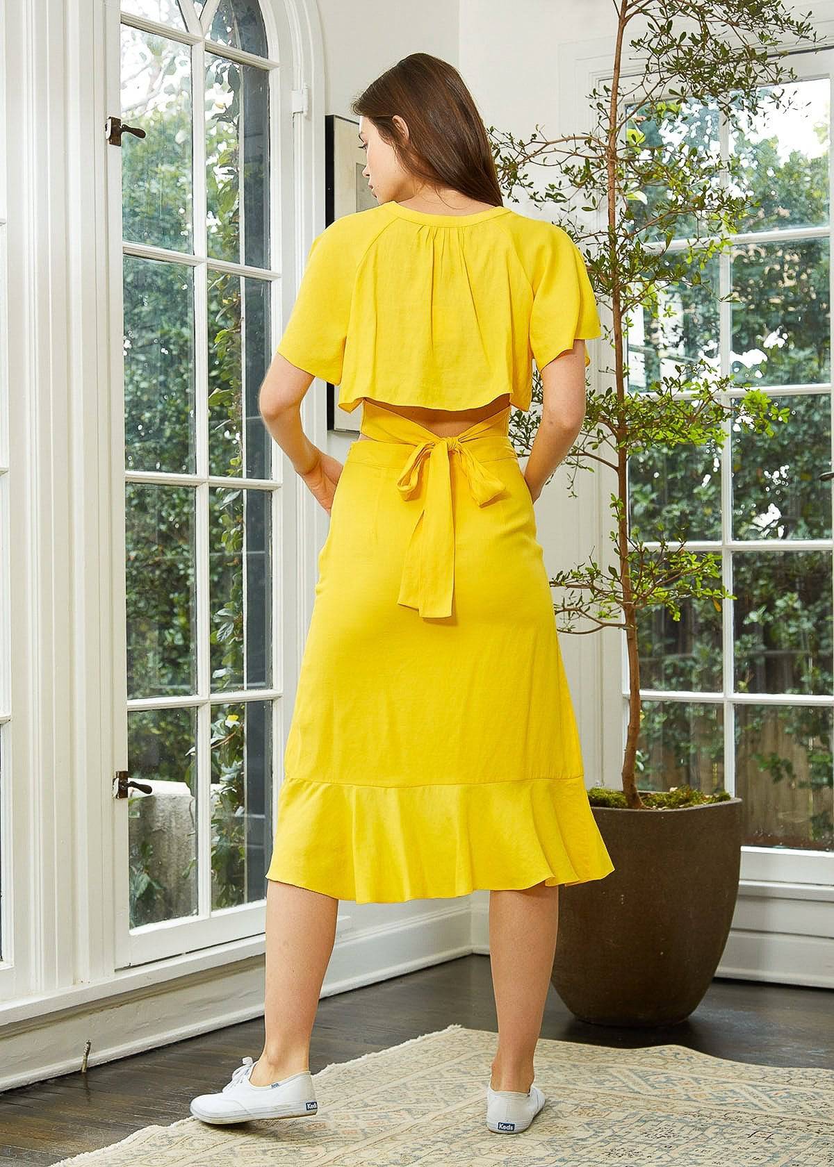 A vibrant yellow women's skirt featuring an asymmetrical hem and button front design, perfect for a flirty and stylish look.