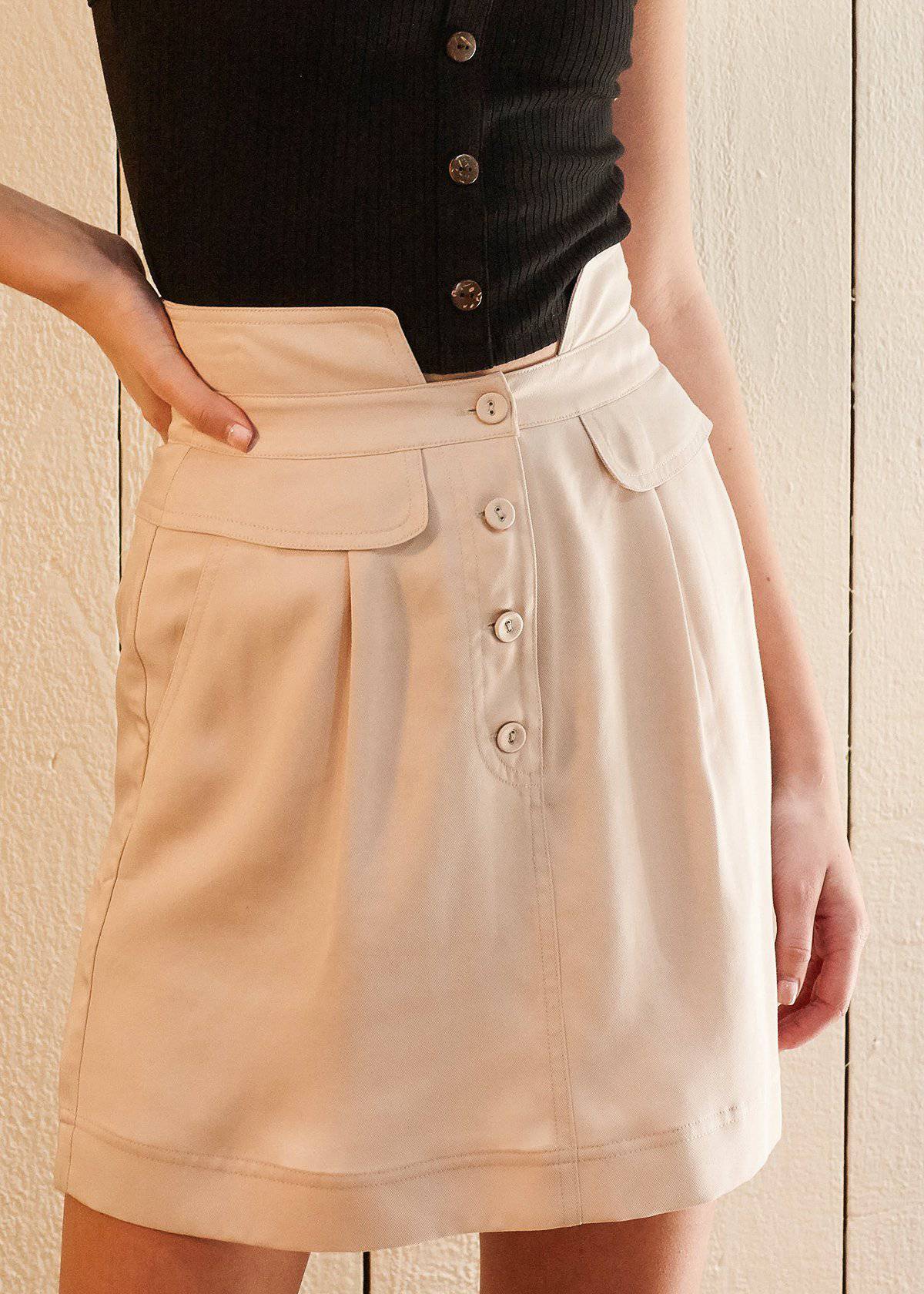 Women's high waisted utility skirt in sand color, featuring a flared design, side pockets, and button fly closure, made from soft Tencel twill fabric.