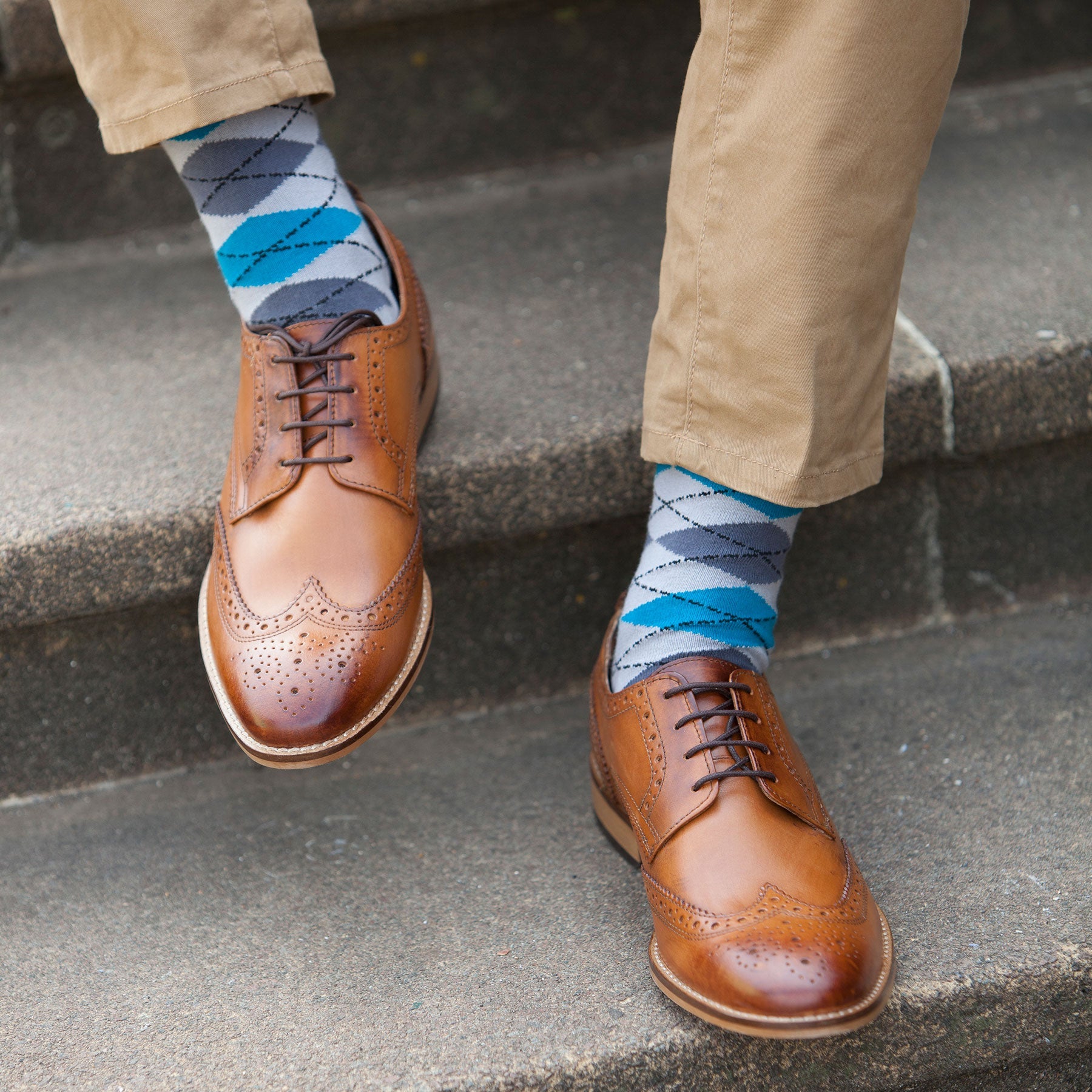 A pair of Argyle men's socks in grey and blue with black heel, cuff, and toe, showcasing a modern twist on a classic design.