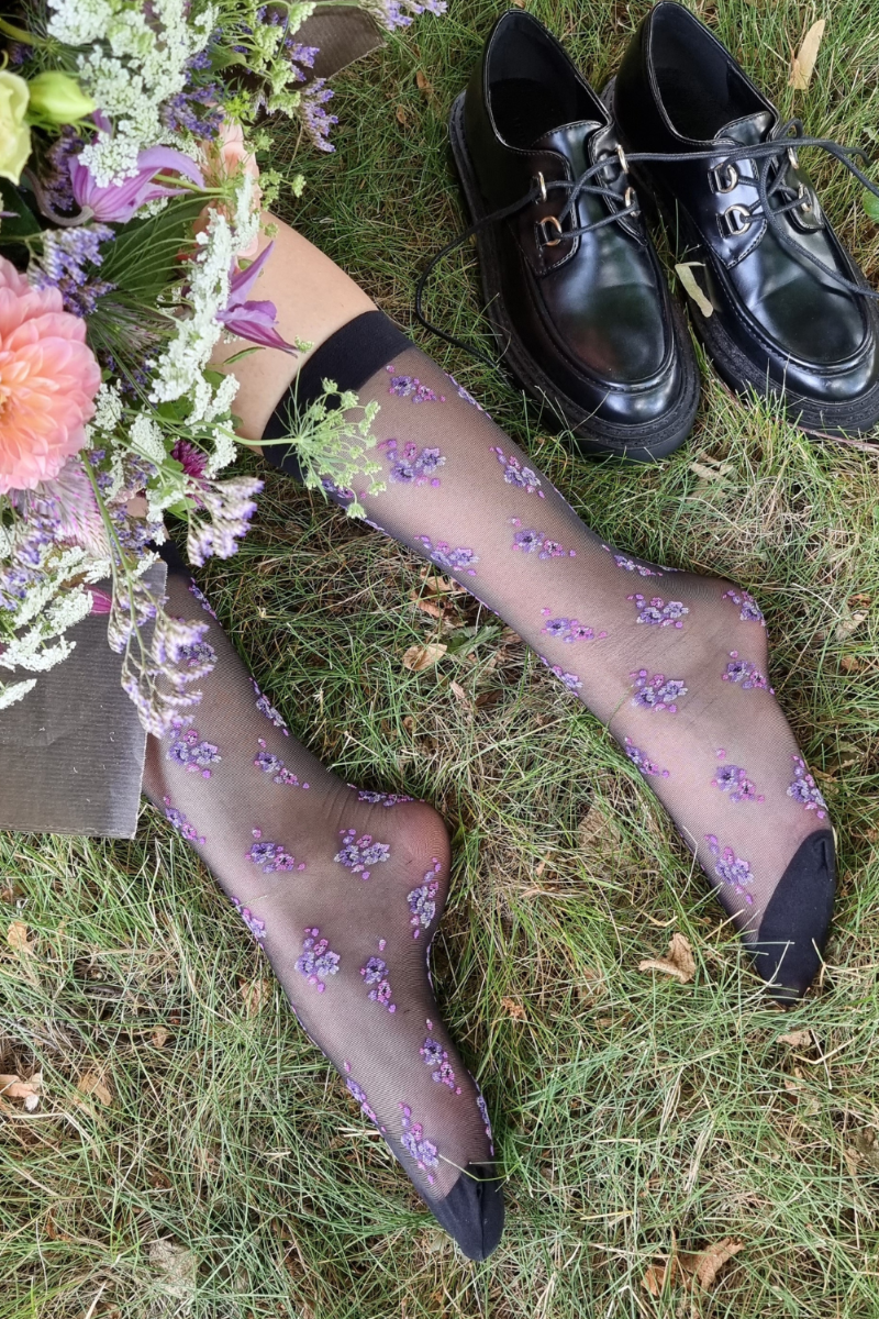 ARINA sheer black socks featuring a delicate purple floral pattern, designed for women with a comfortable rubber edge.