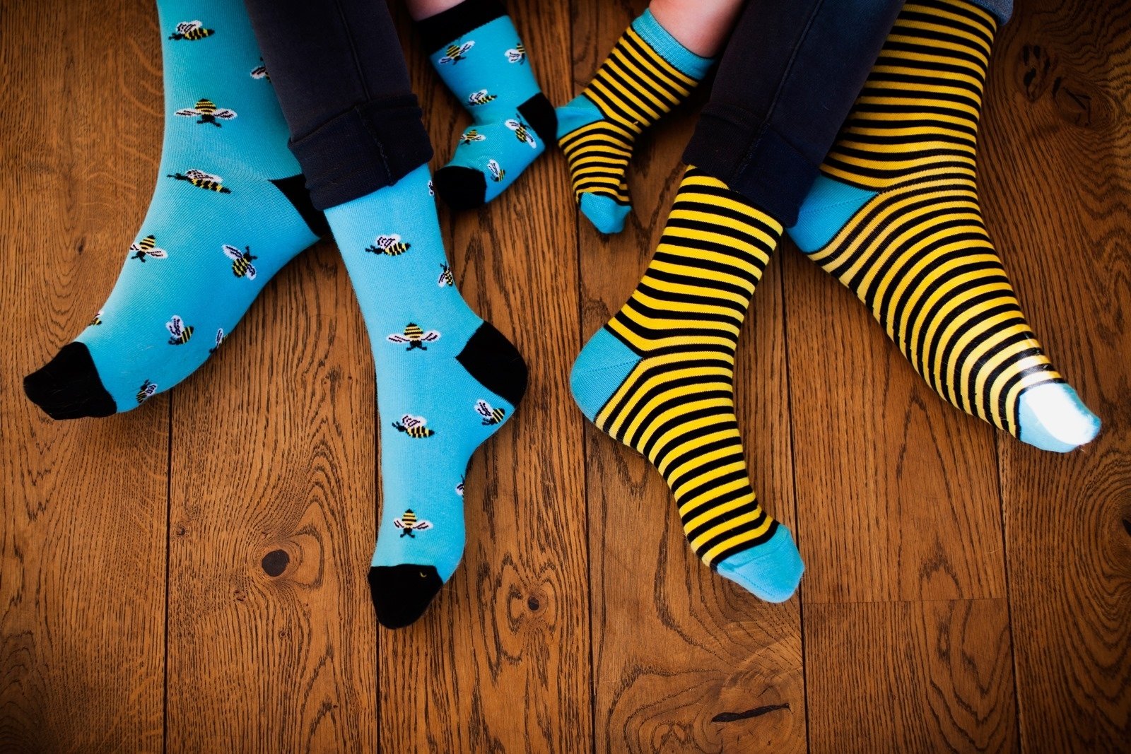 A pair of BUG men's cotton socks featuring one striped sock and one with bees, in vibrant blue and yellow colors.