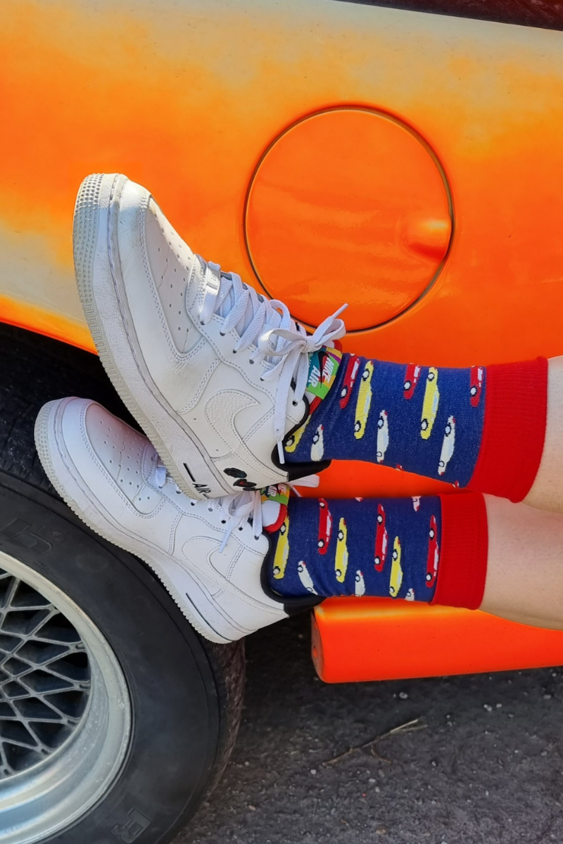 A pair of blue socks featuring colorful car designs in white, red, and yellow, perfect for men who love automotive themes.