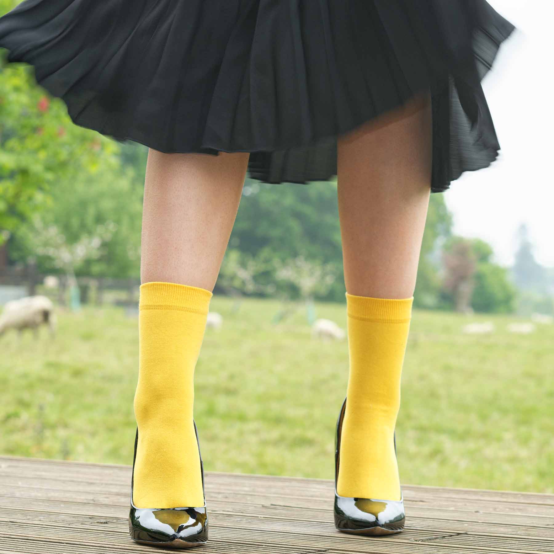 A pair of vibrant yellow classic women's socks made from luxurious Egyptian cotton, showcasing a seamless toe design.