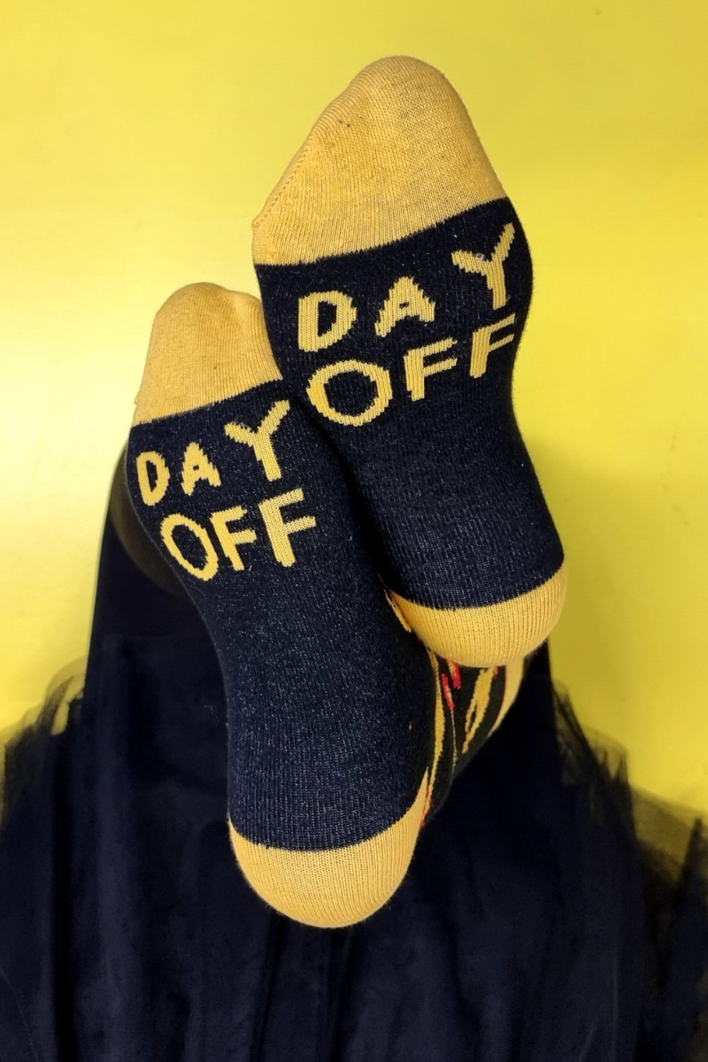 Black DAY OFF socks featuring yellow chickens and text under the sole.