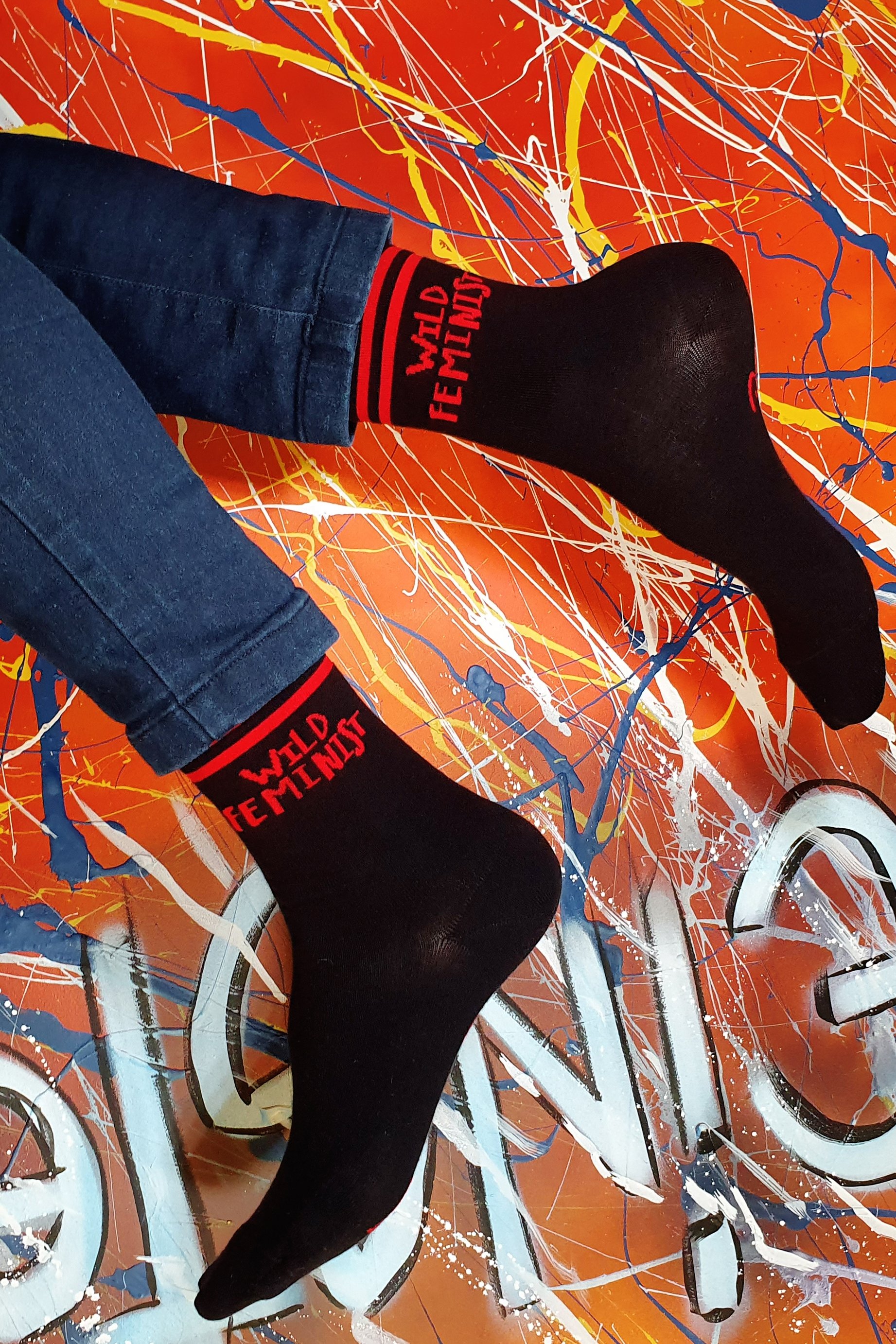 A pair of black cotton socks for women featuring the text 'WILD FEMINIST' on the side and 'Don't tell me to calm down' on the sole.