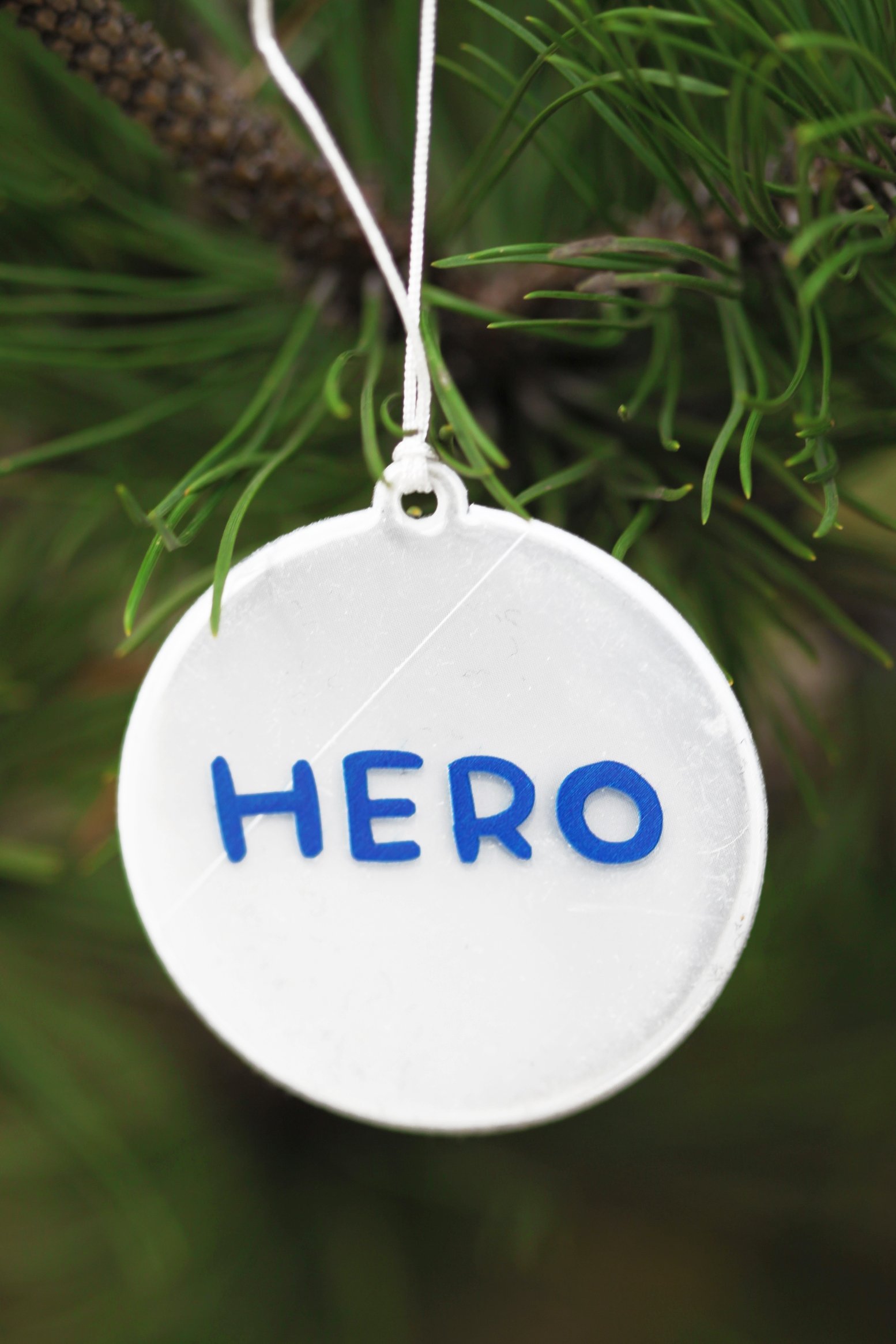 HERO reflector featuring blue writing on a circular design, measuring 60mm in diameter with a 33cm string for attachment.