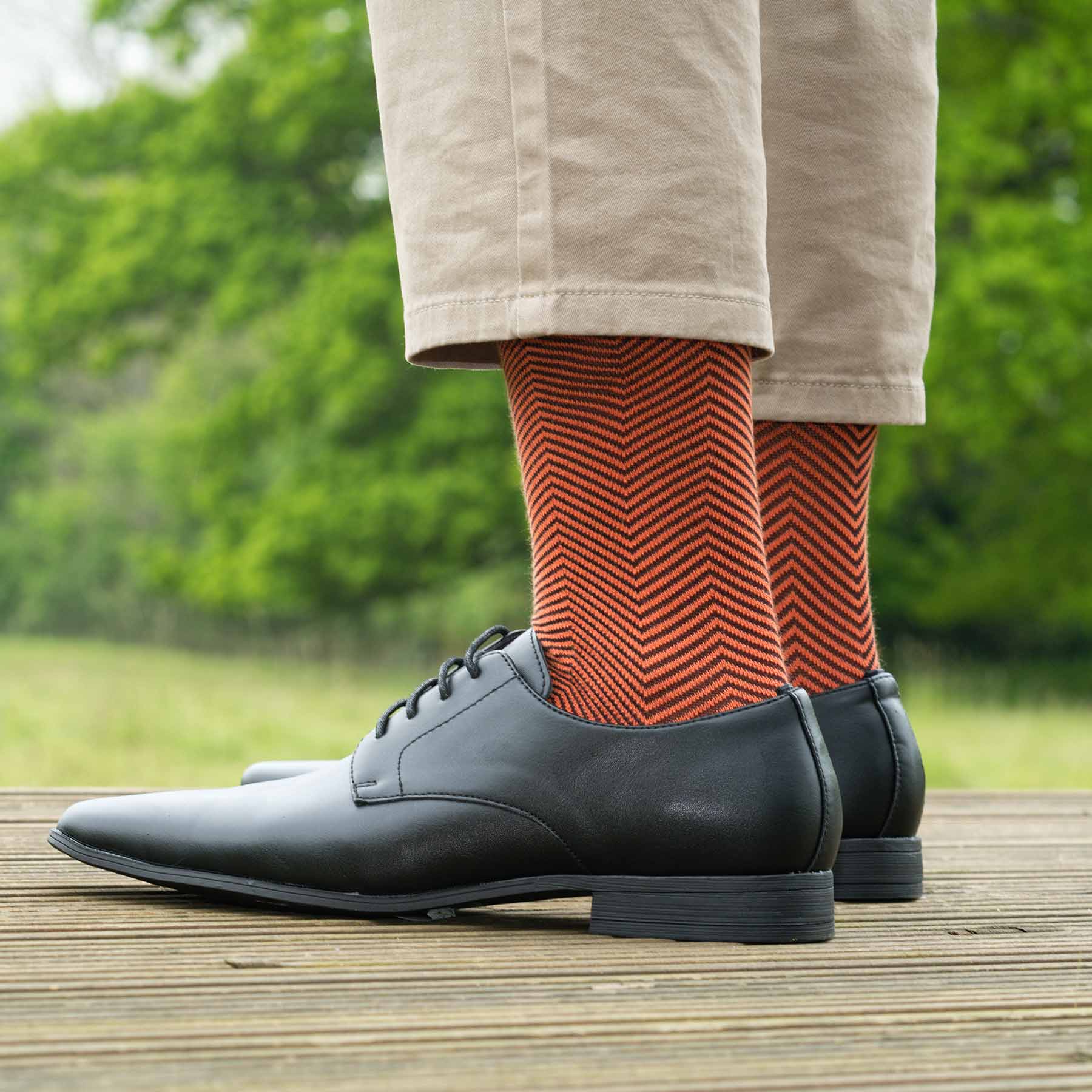 Lux Taylor Men's Socks in vibrant orange with black zigzag pattern and cream heel and toe, showcasing luxury and style.