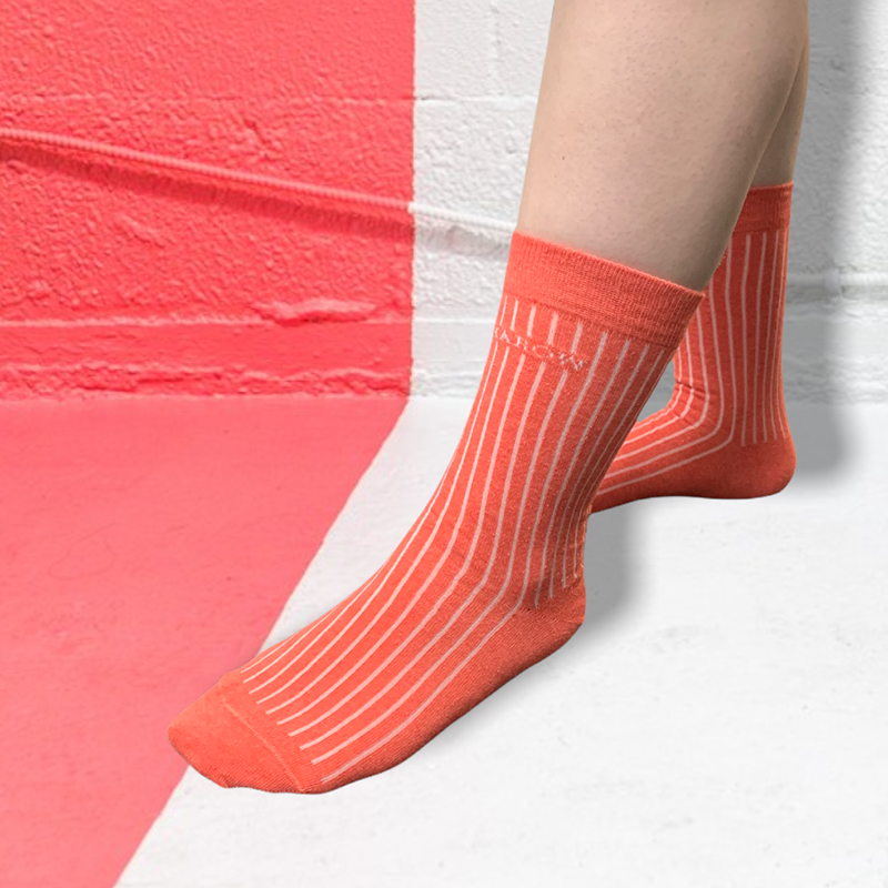 A pair of coral pink ribbed women's socks made from recycled materials, showcasing a stylish and eco-friendly design.