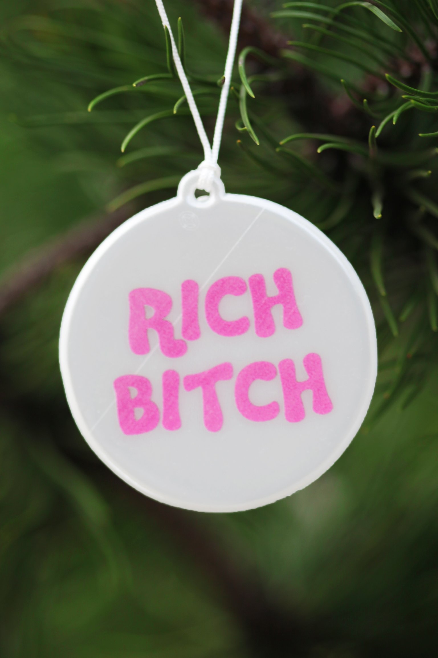 A stylish pink reflector with the text 'RICH BITCH', measuring 60mm in diameter and attached to a 33cm string.