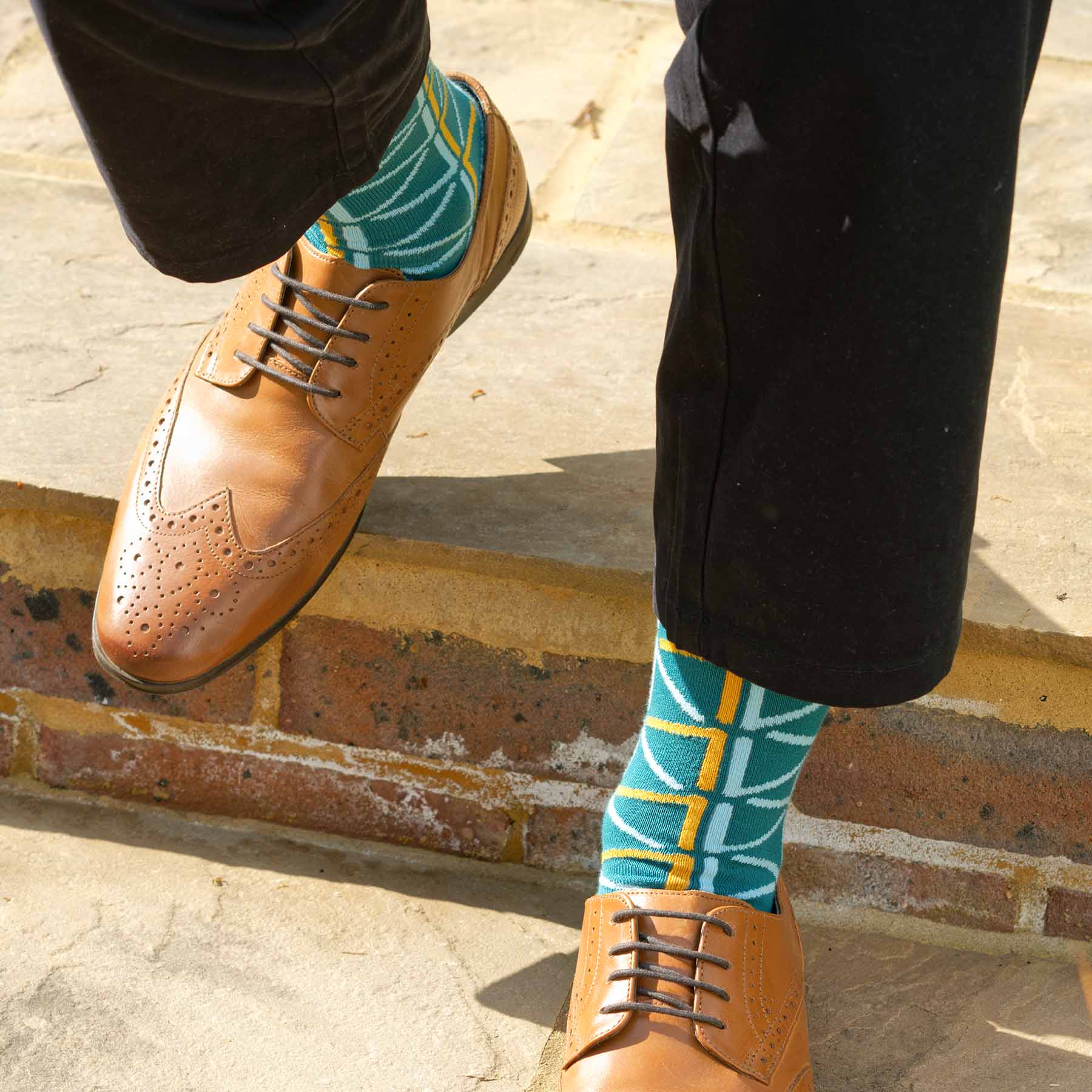 A pair of teal men's luxury socks featuring contrasting blue and yellow patterns, made from Supima cotton.