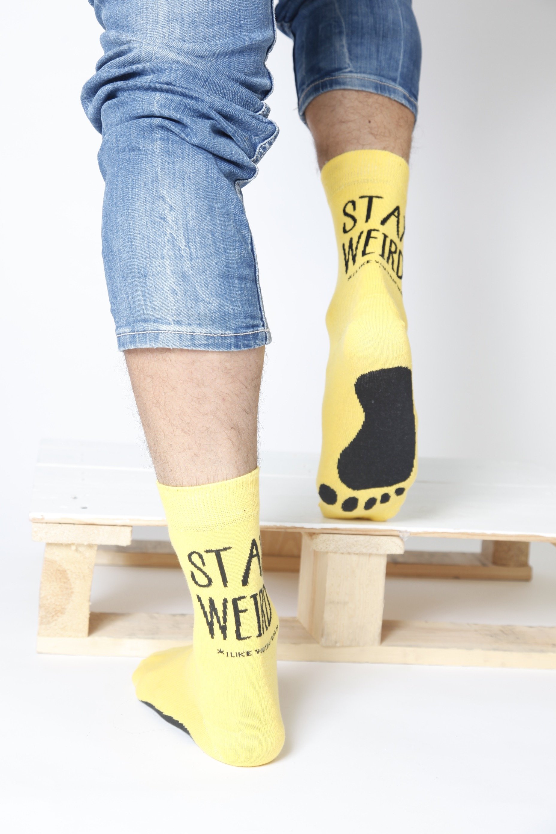 Bright yellow STAY WEIRD men's socks featuring playful text and foot print design.