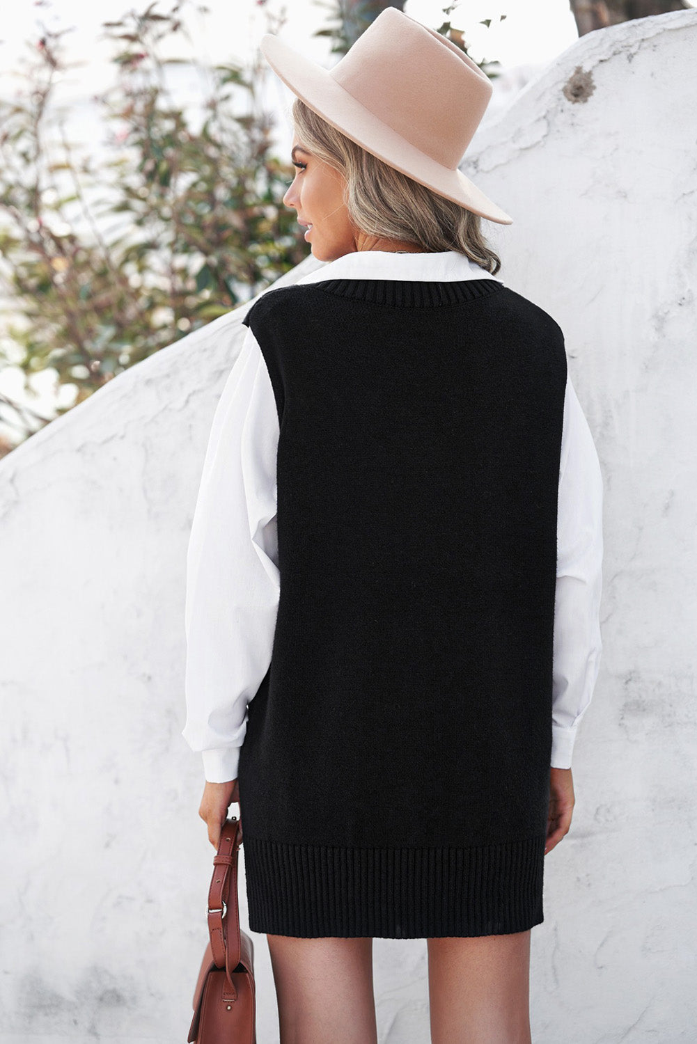 A stylish black knit pullover vest sweater featuring a v-neckline and high-low hemline, perfect for casual layering.