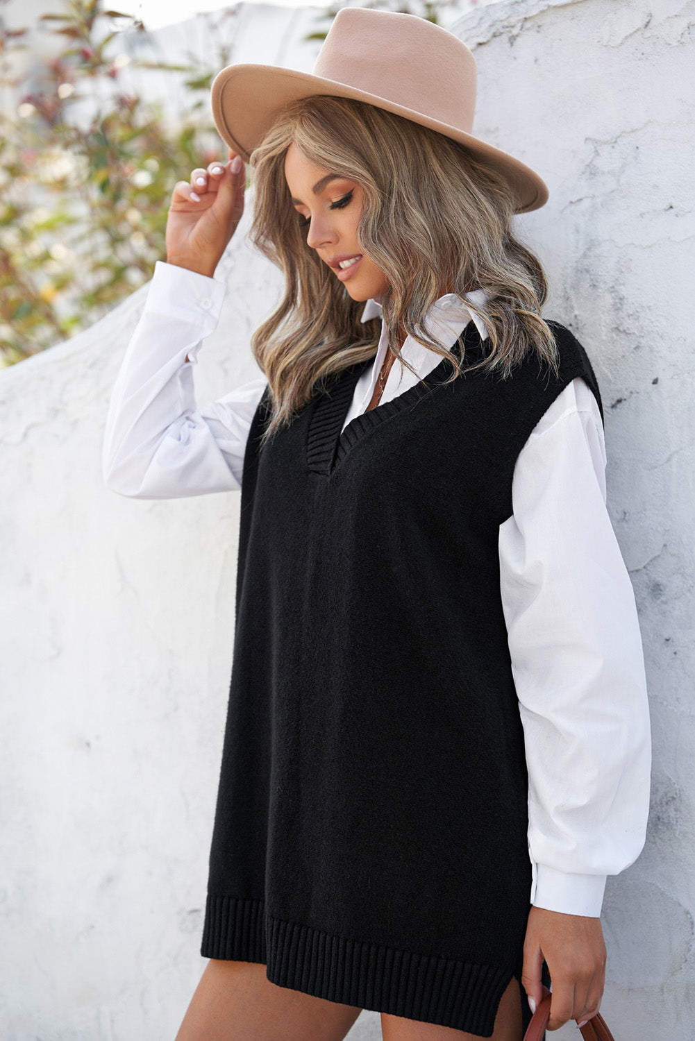 A stylish black knit pullover vest sweater featuring a v-neckline and high-low hemline, perfect for casual layering.