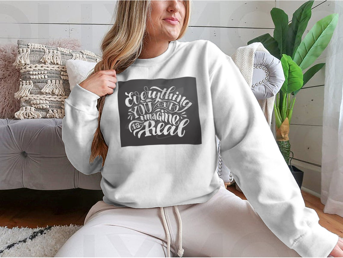 A cute hand-drawn doodle T-shirt featuring the motivational phrase 'Everything You Can Imagine Is Real' on a soft cotton fabric.