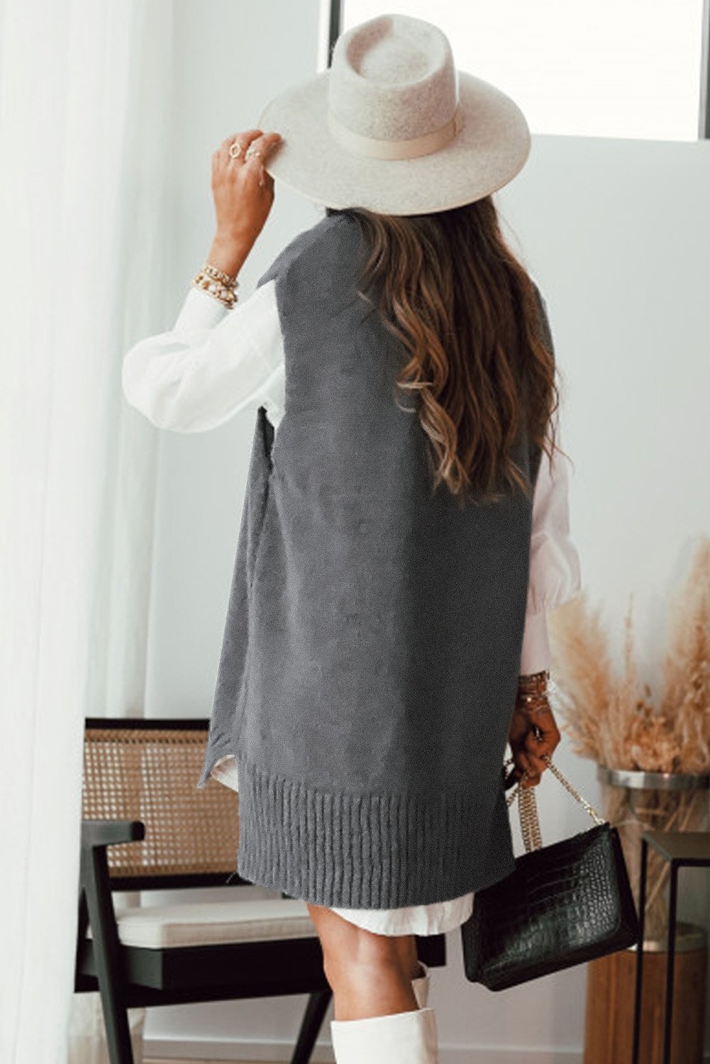 A stylish gray sweater vest featuring a v-neckline, sleeveless design, and high-low hemline, perfect for casual wear.