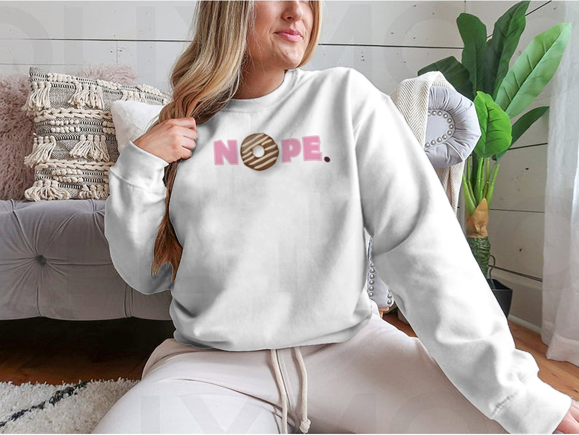 A stylish t-shirt featuring a donut glazed with melted chocolate and pink lettering that says 'Nope'.