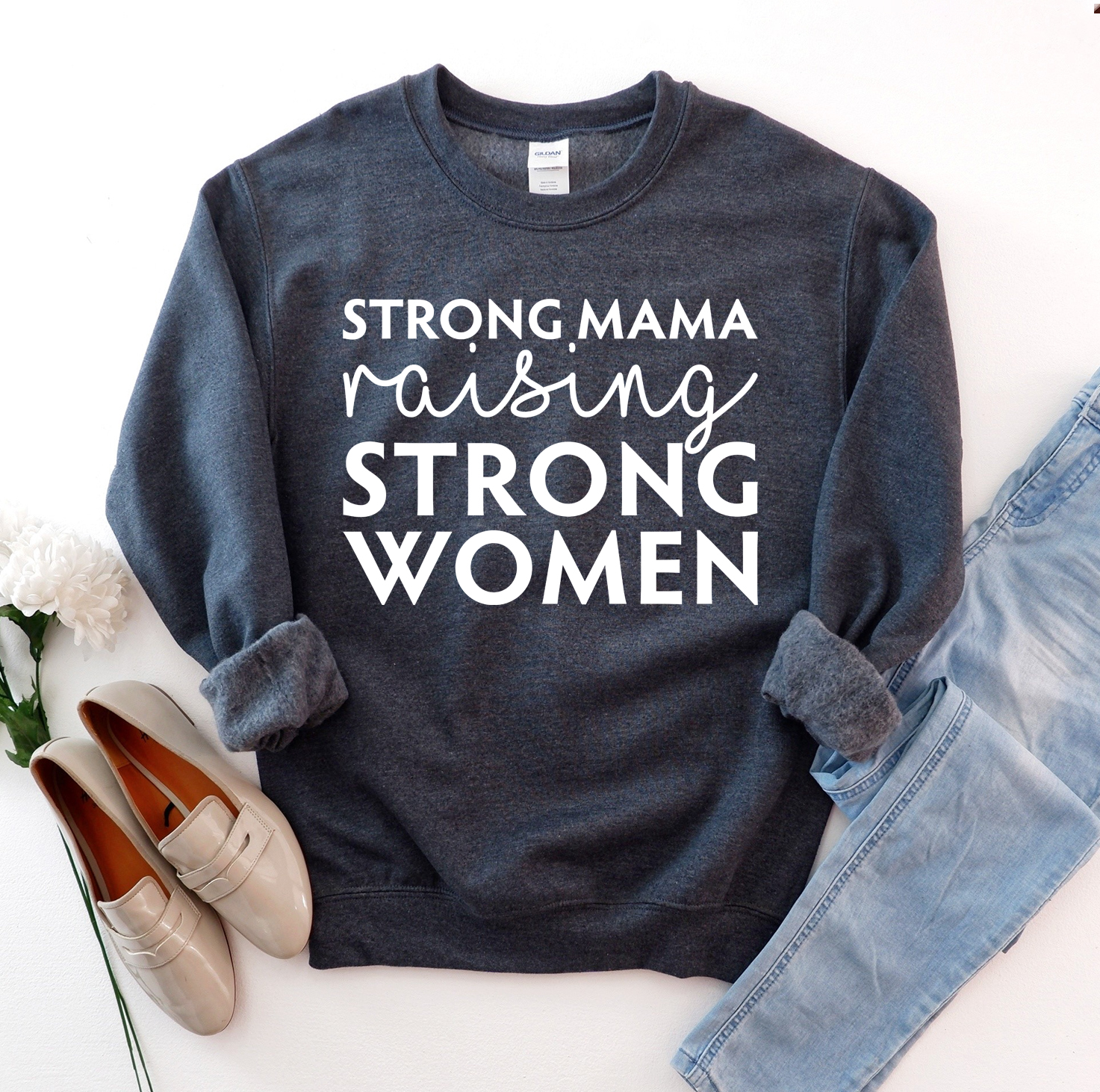 A cozy unisex sweatshirt featuring the phrase 'Strong Mama Raising Strong Women' in a stylish design, perfect for casual wear.