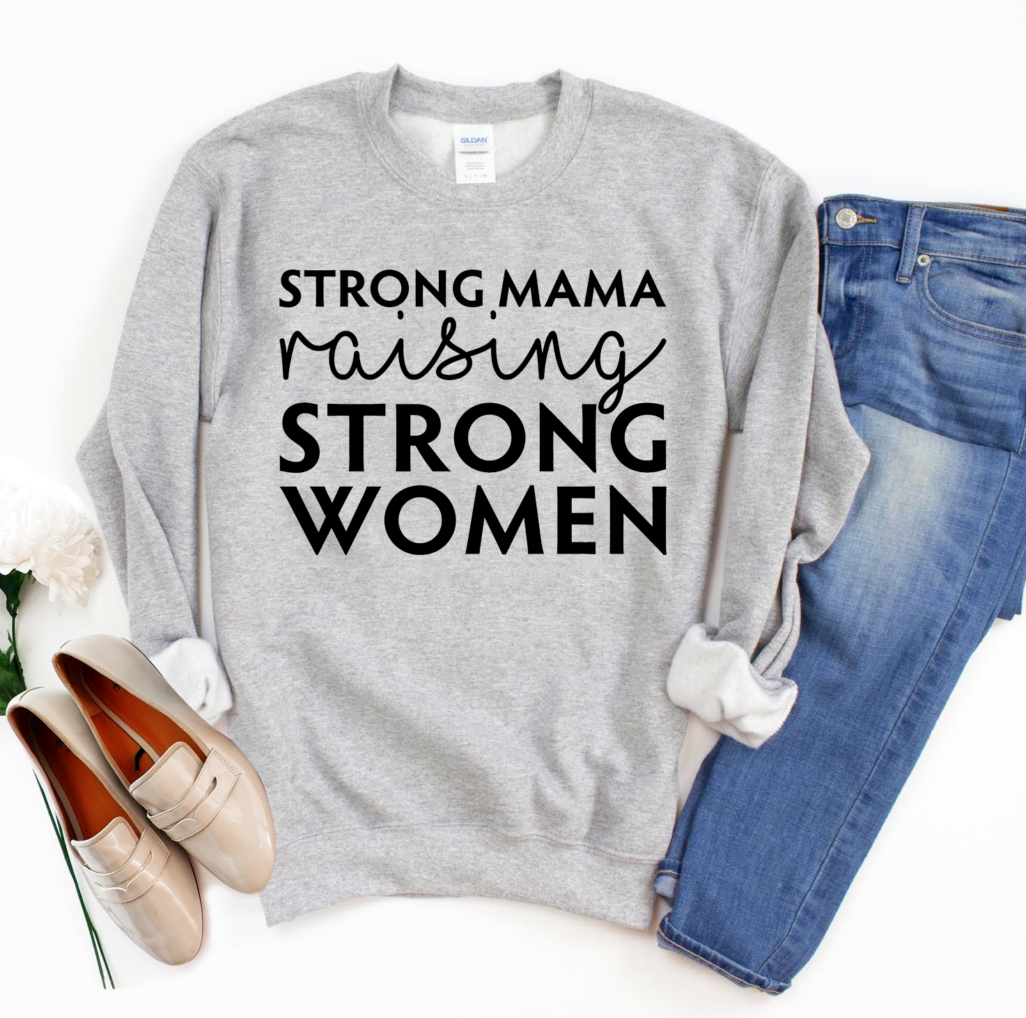 A cozy unisex sweatshirt featuring the phrase 'Strong Mama Raising Strong Women' in a stylish design, perfect for casual wear.