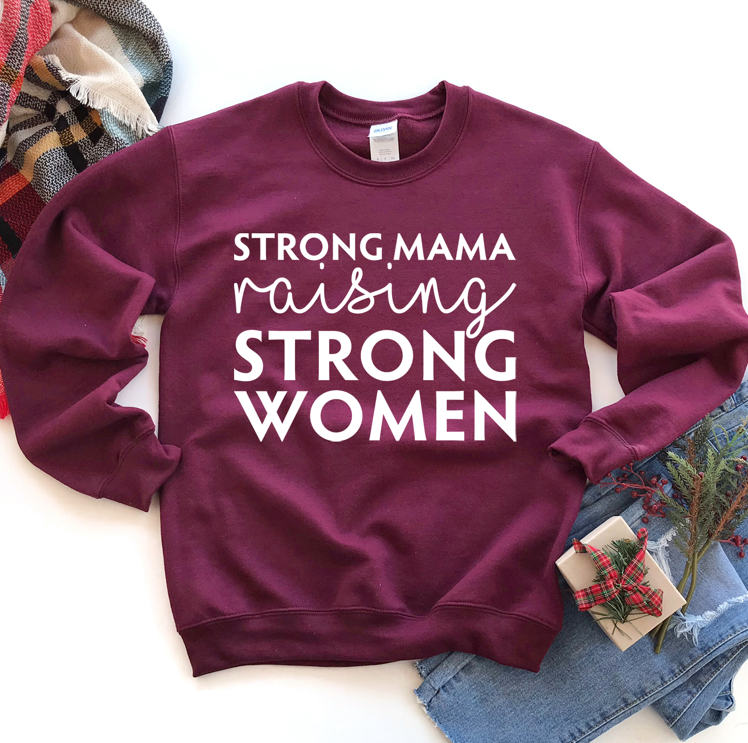 A cozy unisex sweatshirt featuring the phrase 'Strong Mama Raising Strong Women' in a stylish design, perfect for casual wear.