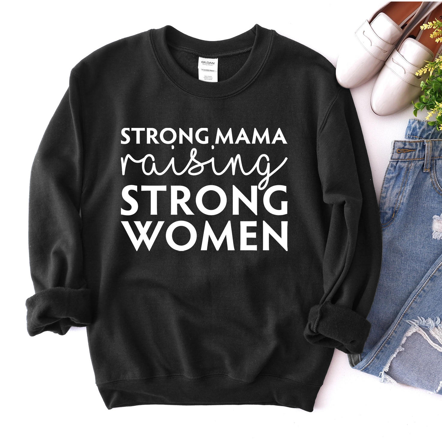 A cozy unisex sweatshirt featuring the phrase 'Strong Mama Raising Strong Women' in a stylish design, perfect for casual wear.