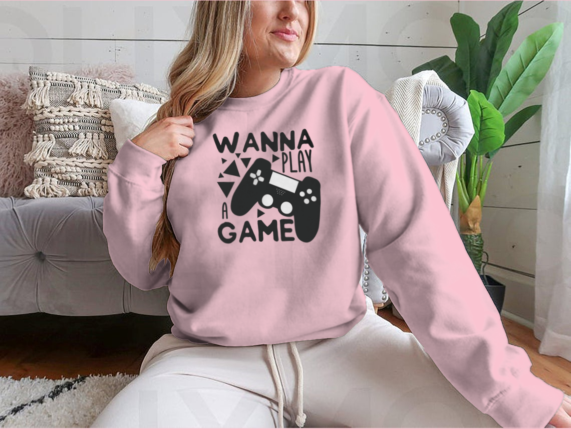 A humorous t-shirt featuring the text 'Wanna Play A Game' with a black gaming controller design, made from soft cotton fabric.