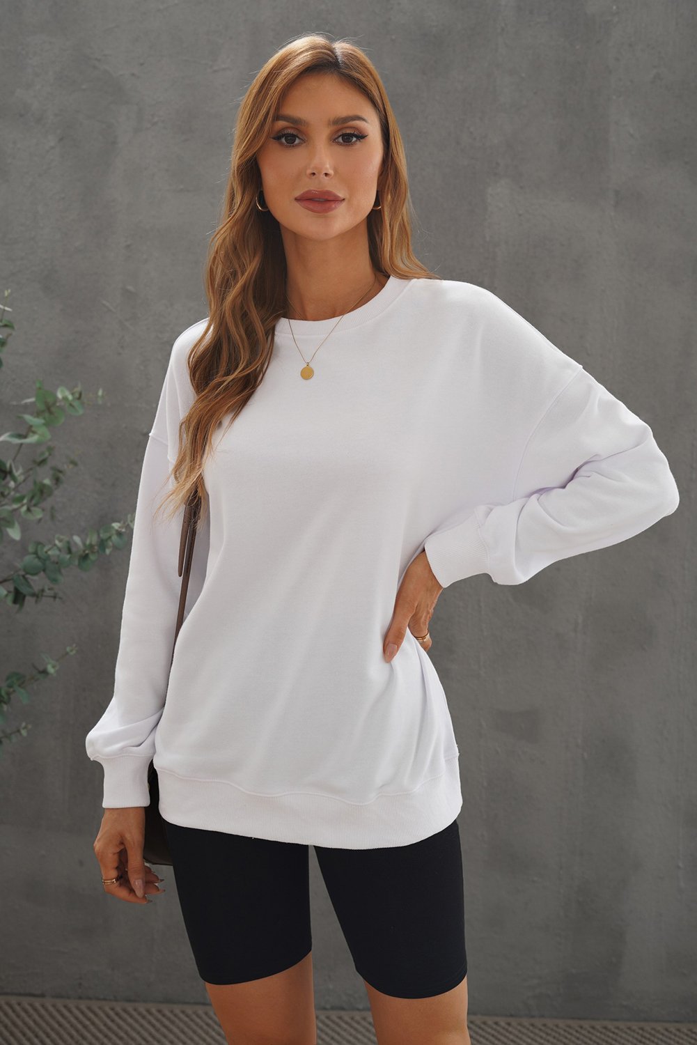 A cozy white oversized sweatshirt with a drop shoulder design, perfect for casual wear in fall and winter.