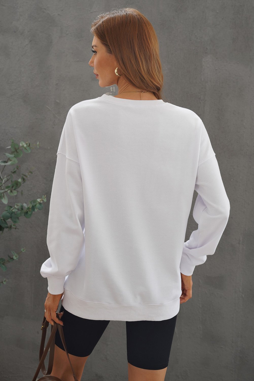 A cozy white oversized sweatshirt with a drop shoulder design, perfect for casual wear in fall and winter.