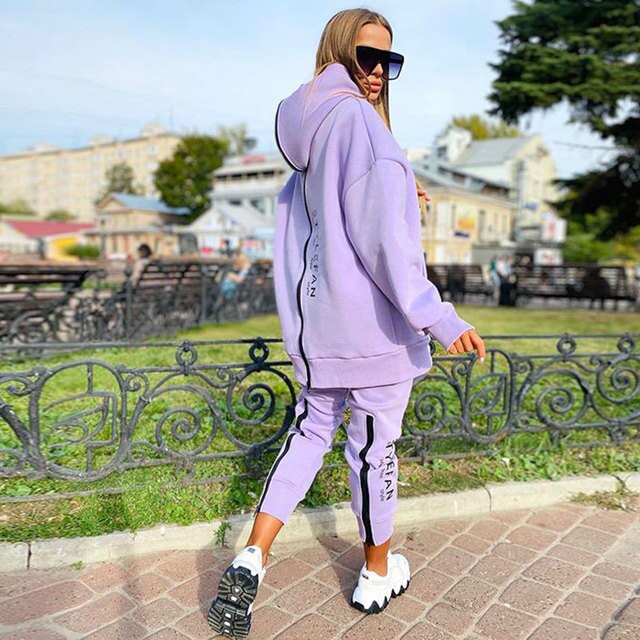 Women wearing an oversized letter print sweatshirt and ankle-length pants tracksuit set, showcasing a stylish and comfortable autumn/winter outfit.