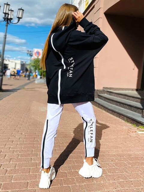 Women wearing an oversized letter print sweatshirt and ankle-length pants tracksuit set, showcasing a stylish and comfortable autumn/winter outfit.