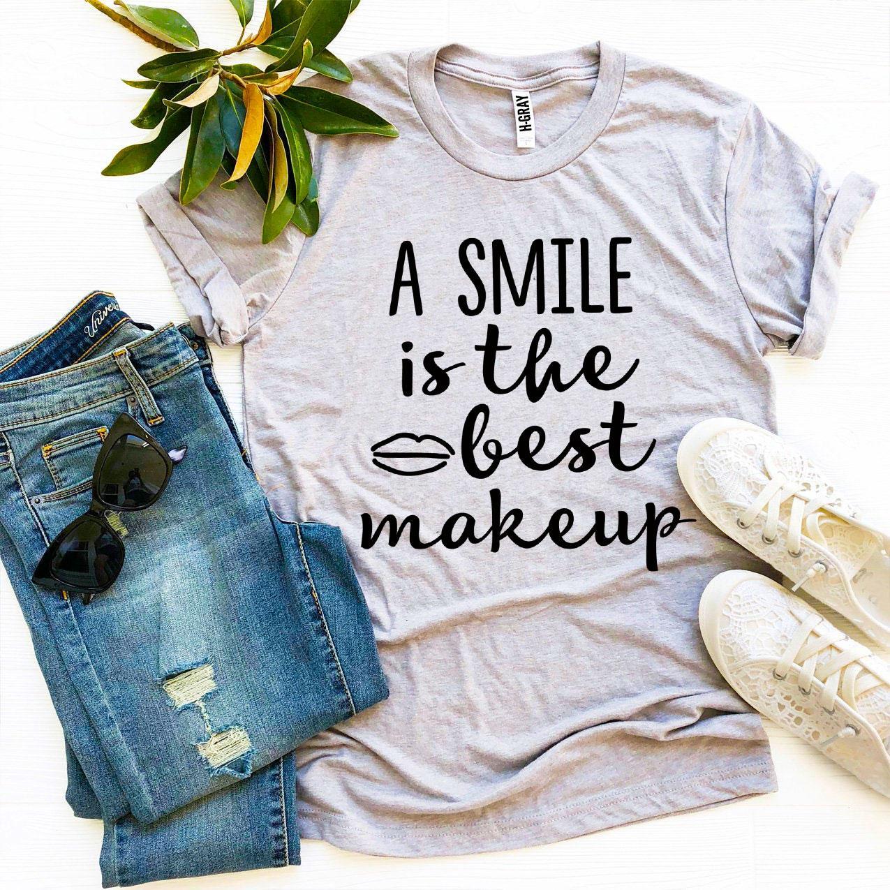 A stylish t-shirt featuring the phrase 'A Smile Is The Best Makeup' printed in vibrant colors on premium cotton fabric.