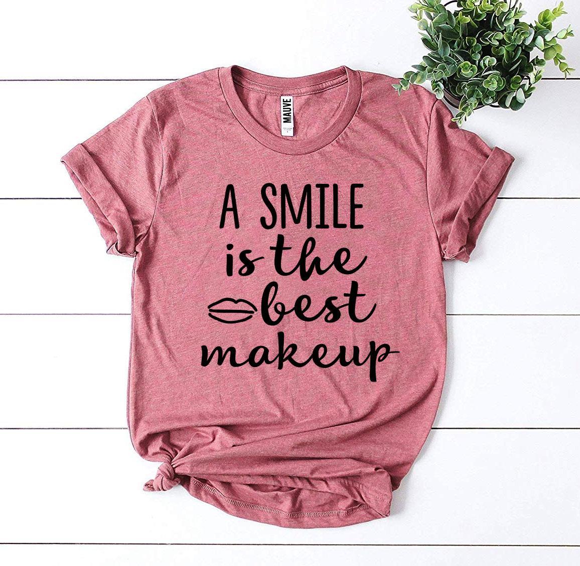 A stylish t-shirt featuring the phrase 'A Smile Is The Best Makeup' printed in vibrant colors on premium cotton fabric.