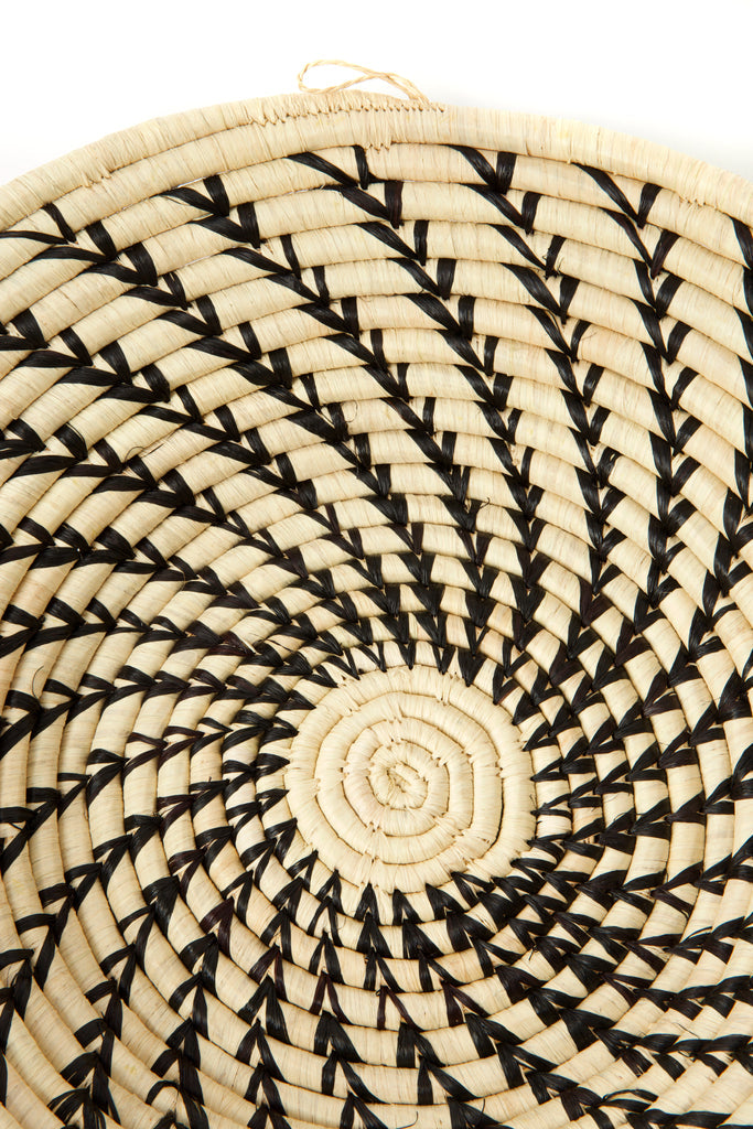 Handcrafted African cream coiled basket with black swirls, showcasing unique design and natural materials.