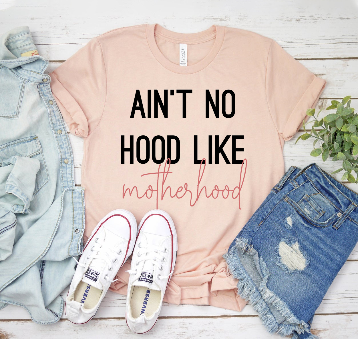 Ain't No Hood Like Motherhood Shirt displayed on a hanger, showcasing its soft fabric and stylish design.