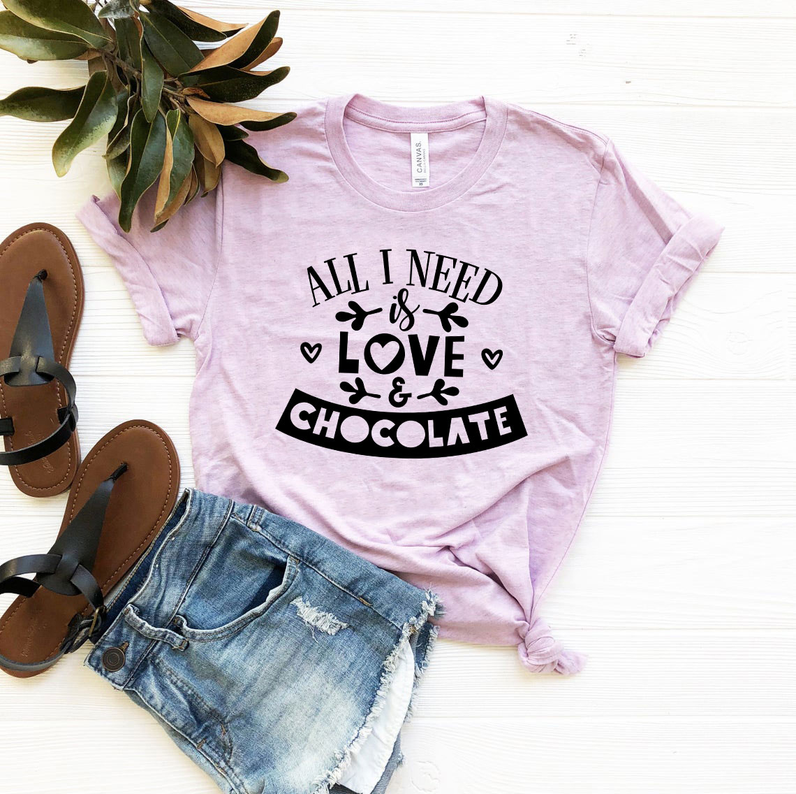 Unisex T-shirt featuring the phrase 'All I Need Is Love & Chocolate' in vibrant print, made from soft ring spun cotton.