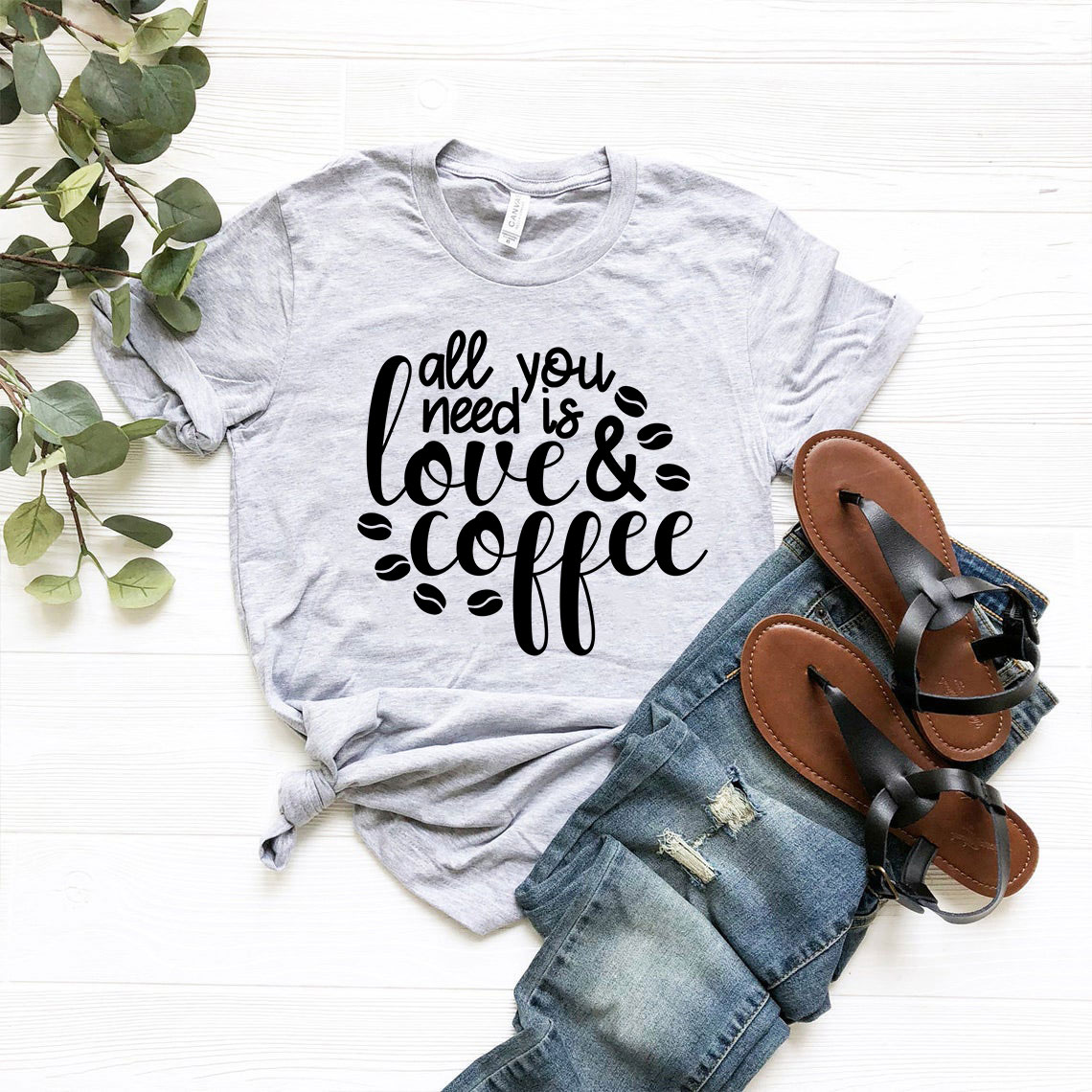 Unisex T-shirt featuring the phrase 'All You Need Is Love And Coffee' in stylish print, available in various colors.