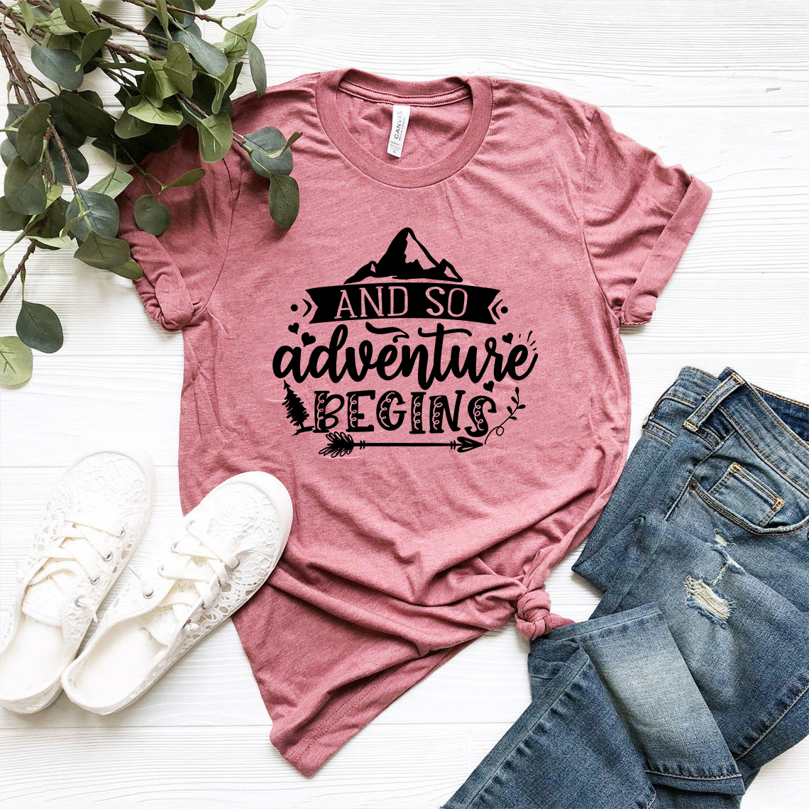 Unisex T-shirt featuring the phrase 'And So Adventure Begins' in a stylish design, made from soft ring spun cotton, available in multiple colors.