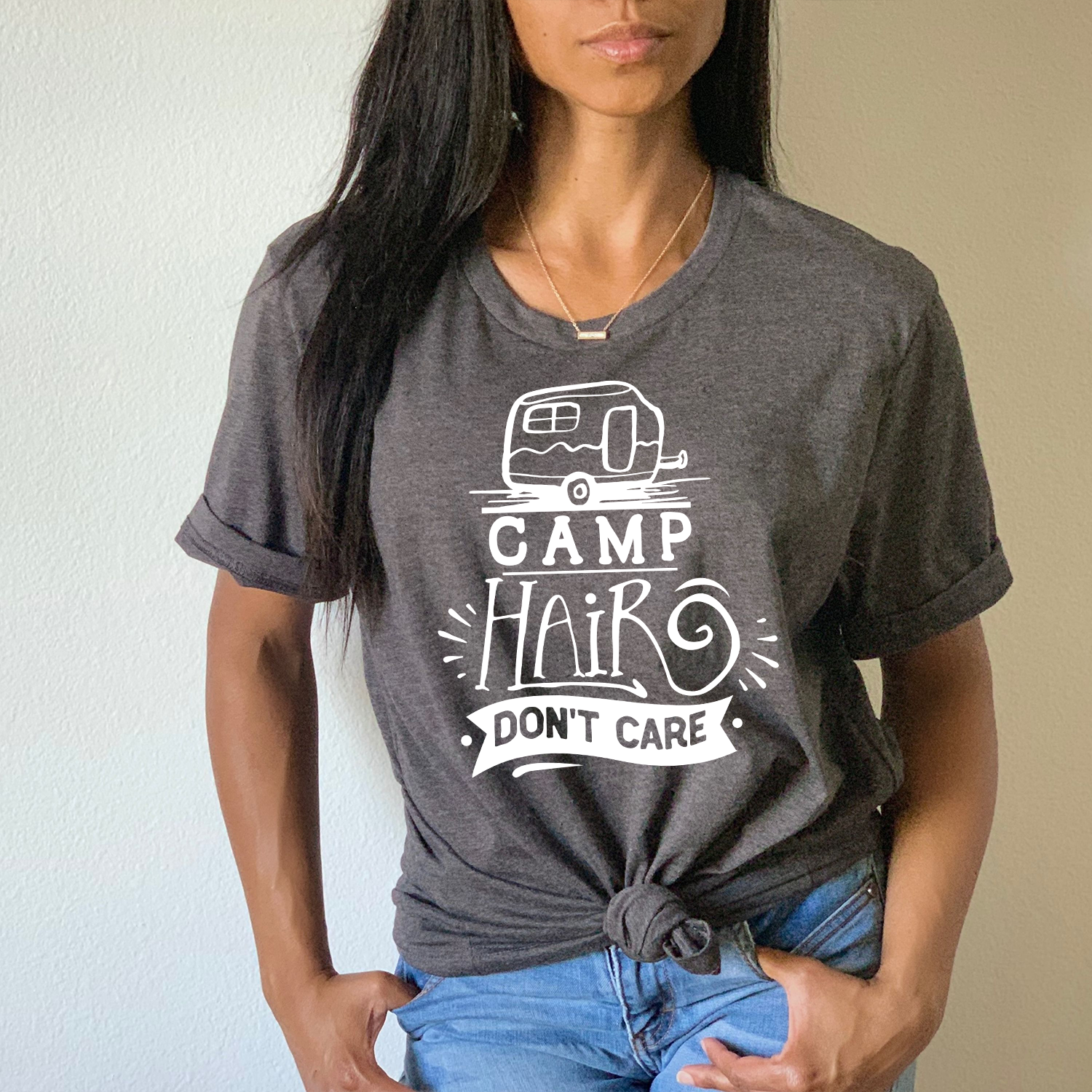 A stylish unisex T-shirt featuring the phrase 'Camp Hair Don't Care' printed in vibrant colors, perfect for outdoor enthusiasts.