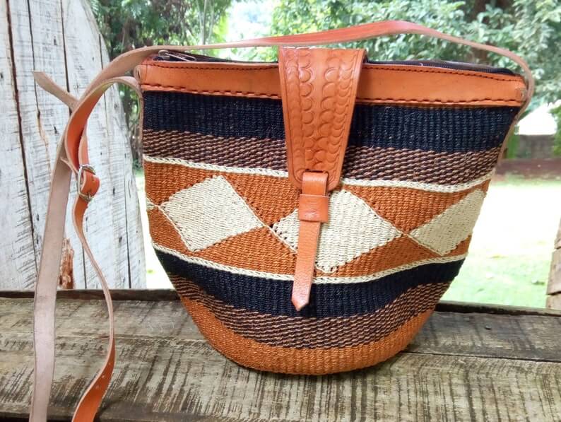 A beautifully handwoven Cross body Kiondo African Bag made from sisal and leather, showcasing intricate patterns and a spacious design.