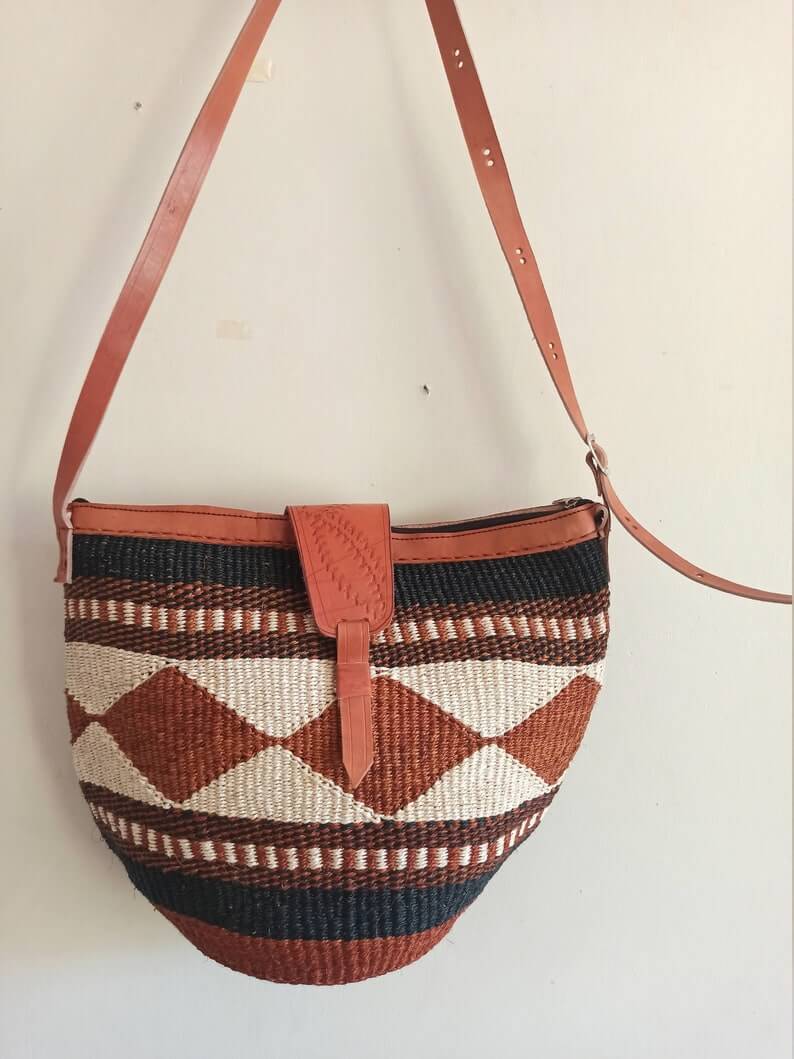 A beautifully handwoven Cross body Kiondo African Bag made from sisal and leather, showcasing intricate patterns and a spacious design.