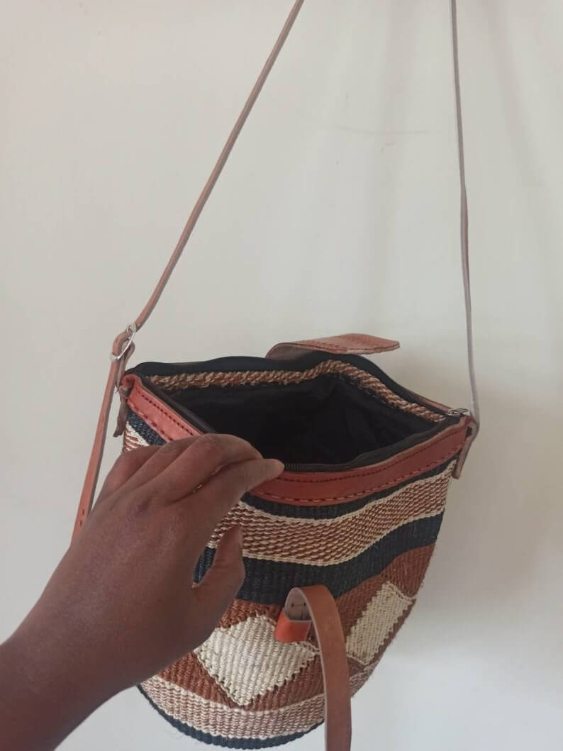 A beautifully handwoven Cross body Kiondo African Bag made from sisal and leather, showcasing intricate patterns and a spacious design.